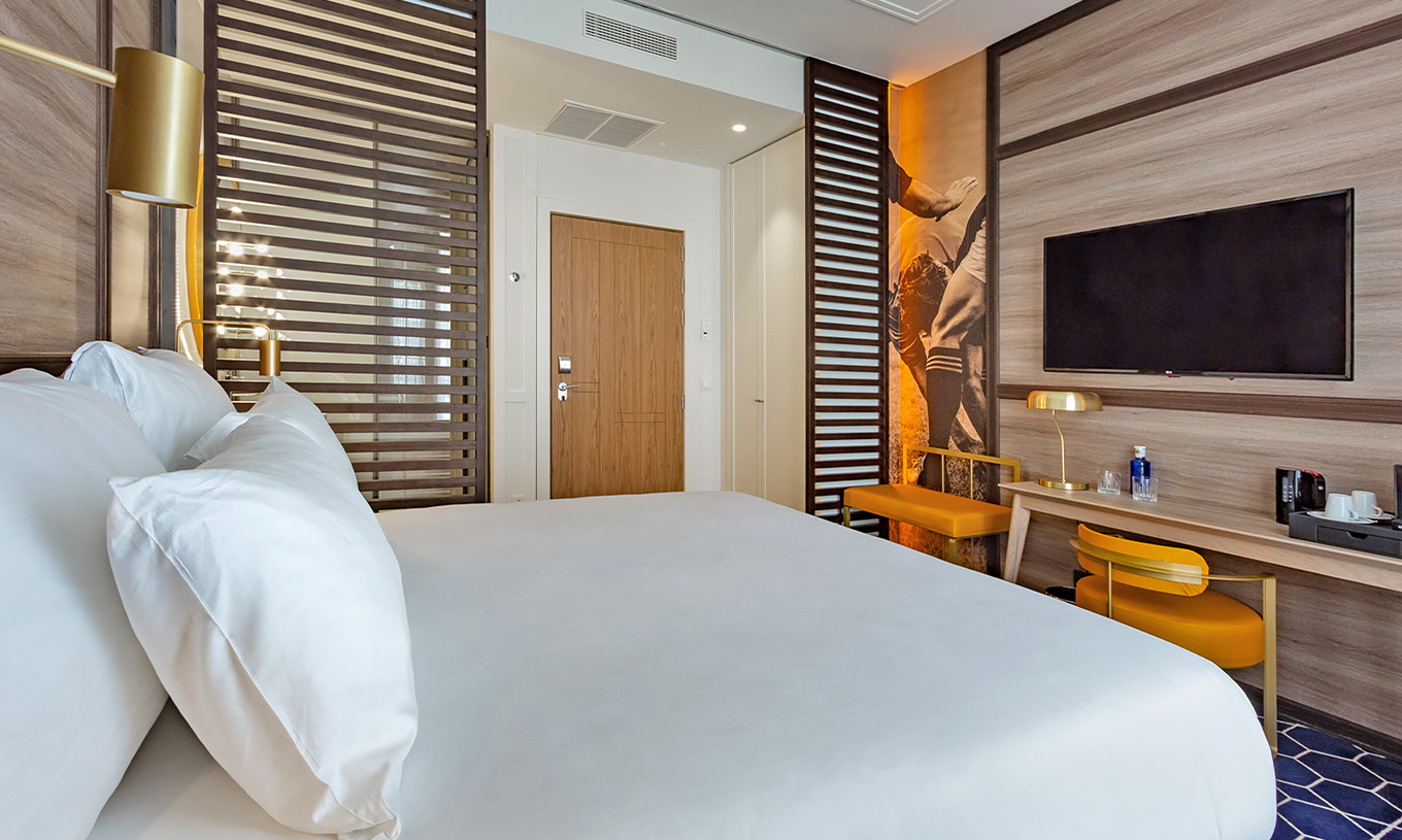 El Premium del Pestana CR7 Gran Vía Madrid tiene cama doble, escritorio con silla y lámpara, banco y televisión