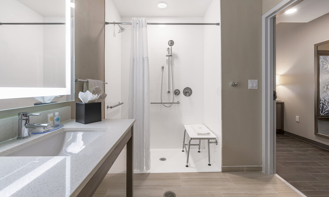 La Suite ADA King del Pestana Orlando Suites Lake Buena Vista tiene baño con ducha adaptada, lavabo y espejo
