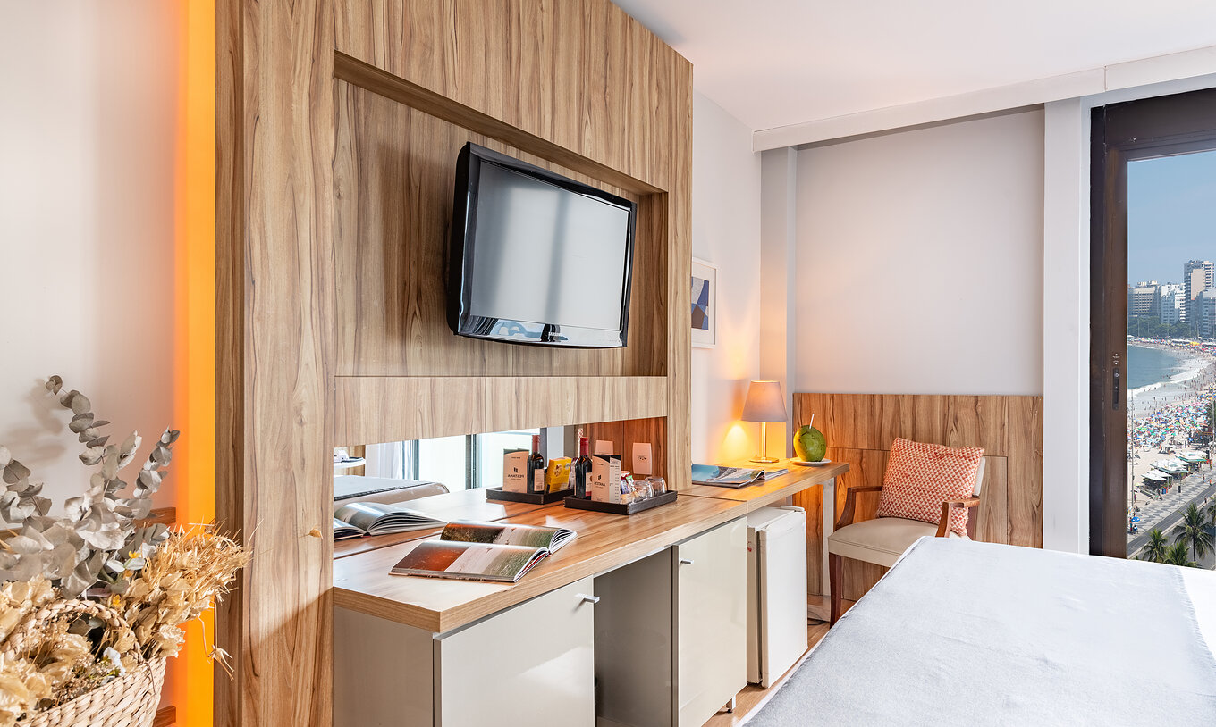 El Queen Vista Lateral al Mar del Pestana Rio Atlântica tiene una televisión enfrente de la cama y una silla acolchada