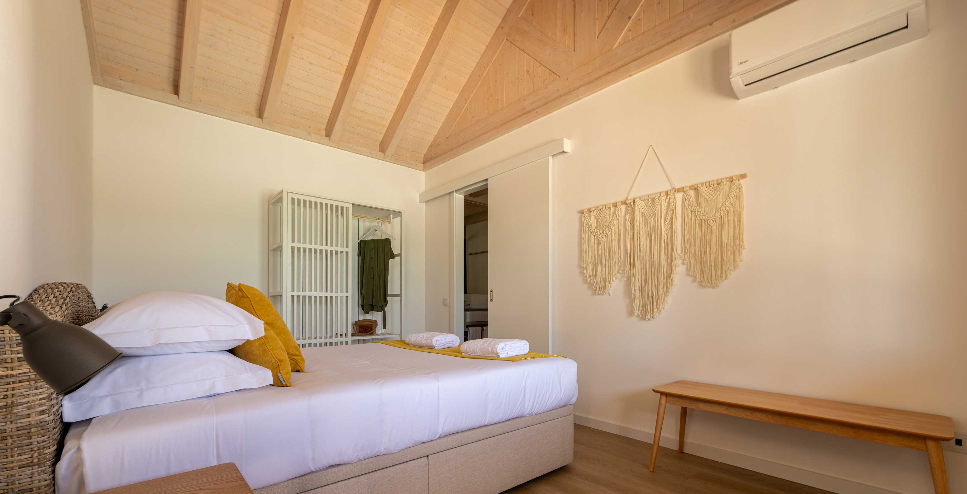 La Standard Green Villa de Pestana Comporta Village Residences tiene un dormitorio minimalista con una cama y un banco