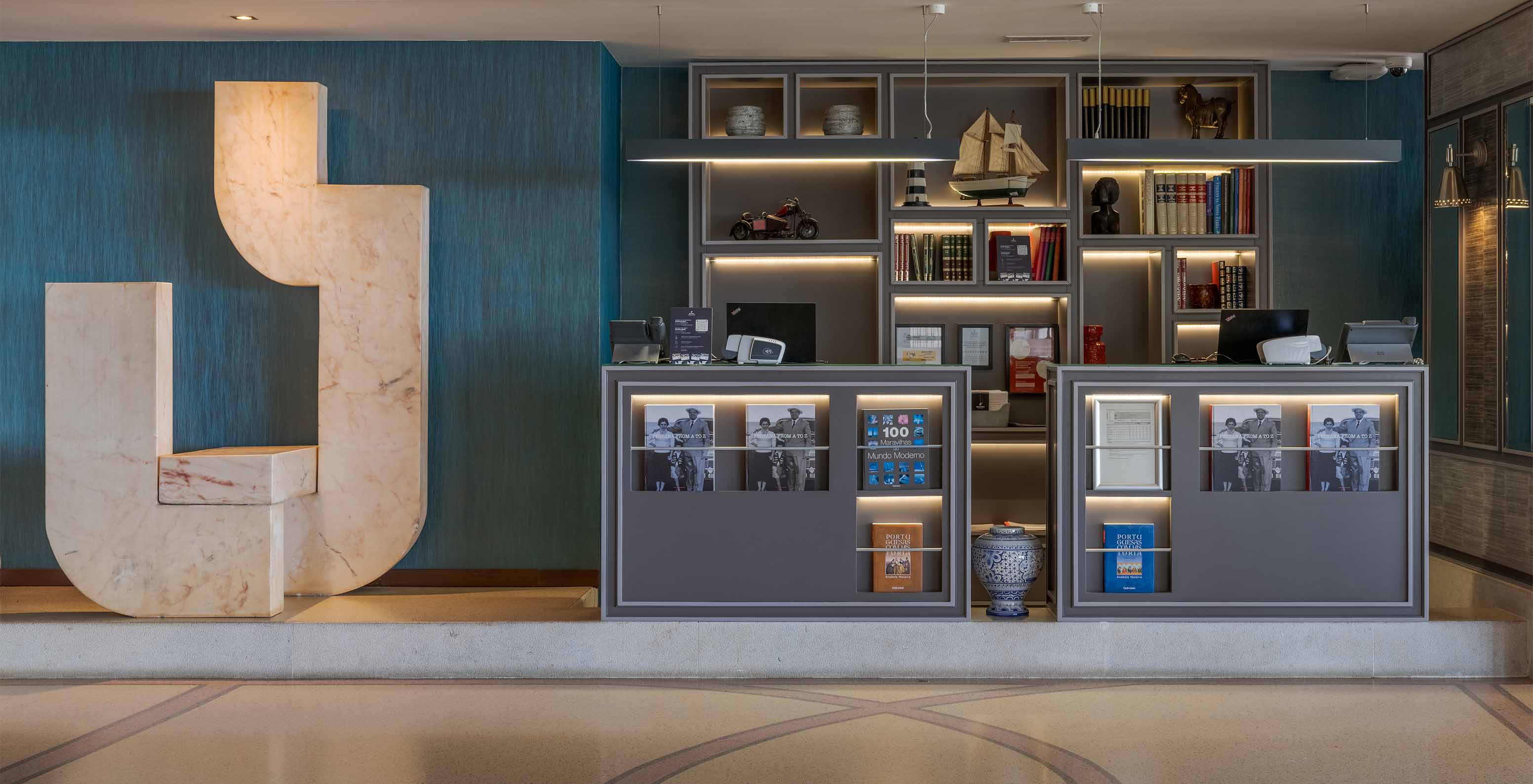 Recepción con decoración elegante, con computadoras y varios libros del Pestana Alvor Praia, Hotel con SPA