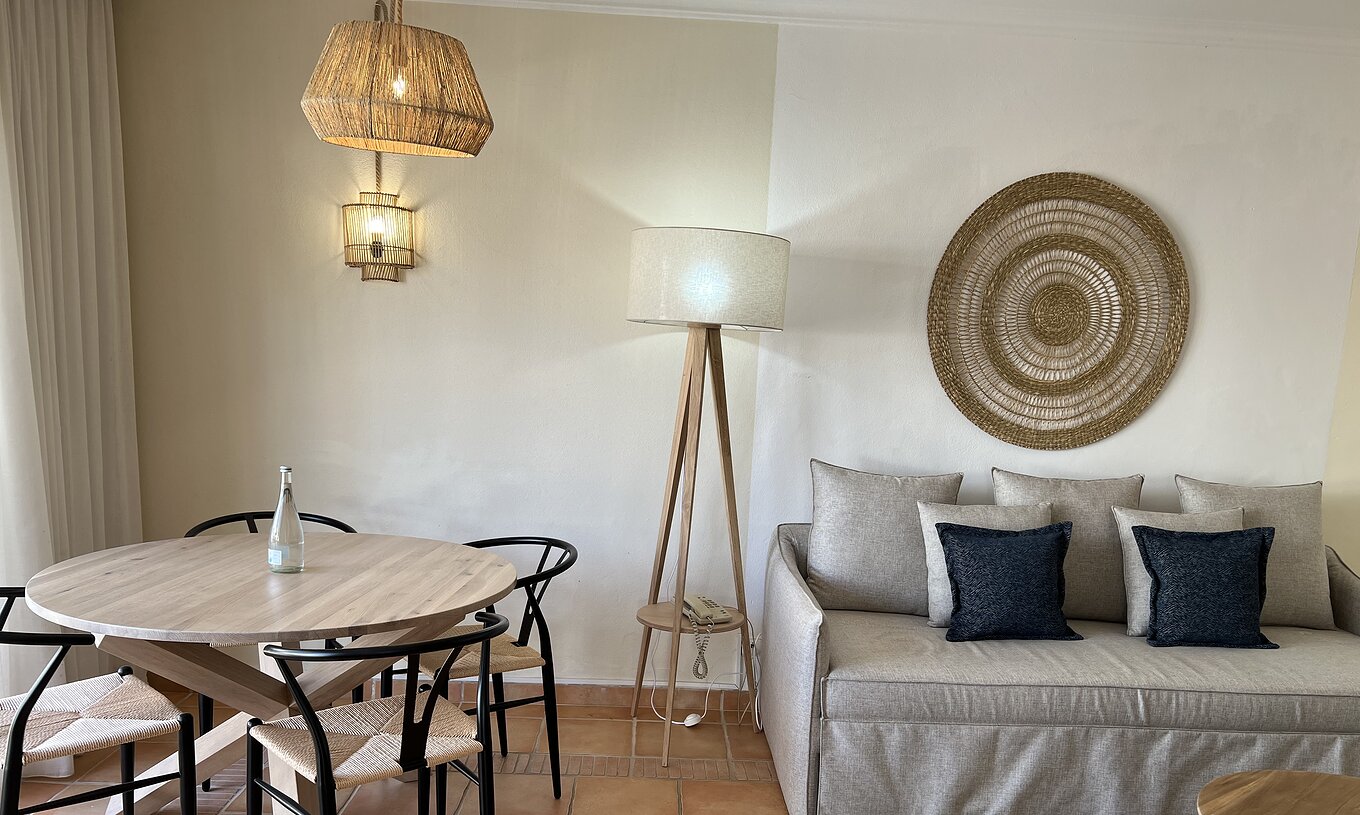 El Apartamento T1 Standard del Pestana Palm Gardens tiene una sala de estar con sofá y almohadas y una mesa redonda