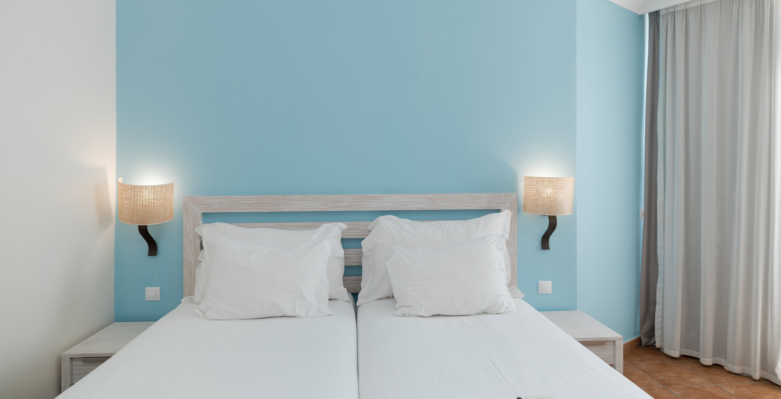 El Deluxe Vista Jardín del Pestana Viking tiene dos camas, dos mesas de noche y papel azul en la pared