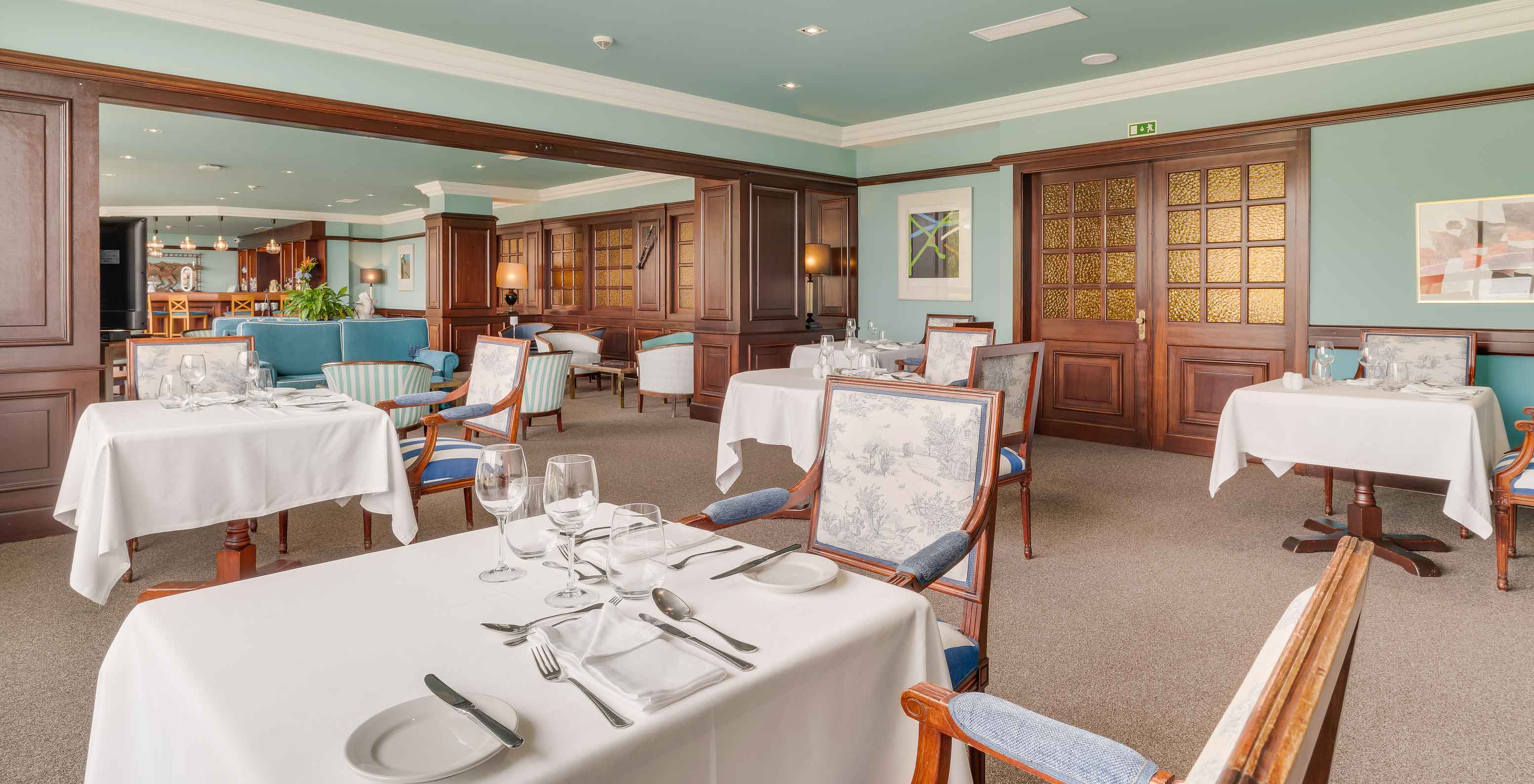 Interior del Bar Aqqua en Pestana Bahia Praia con mesas puestas, sillas clásicas y ambiente acogedor