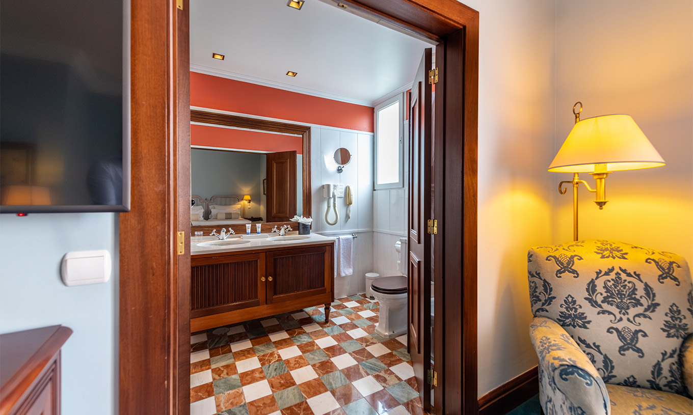 El Deluxe del Pestana Palace Lisboa tiene un baño con dos lavabos en mueble de madera, espejo y sanitario