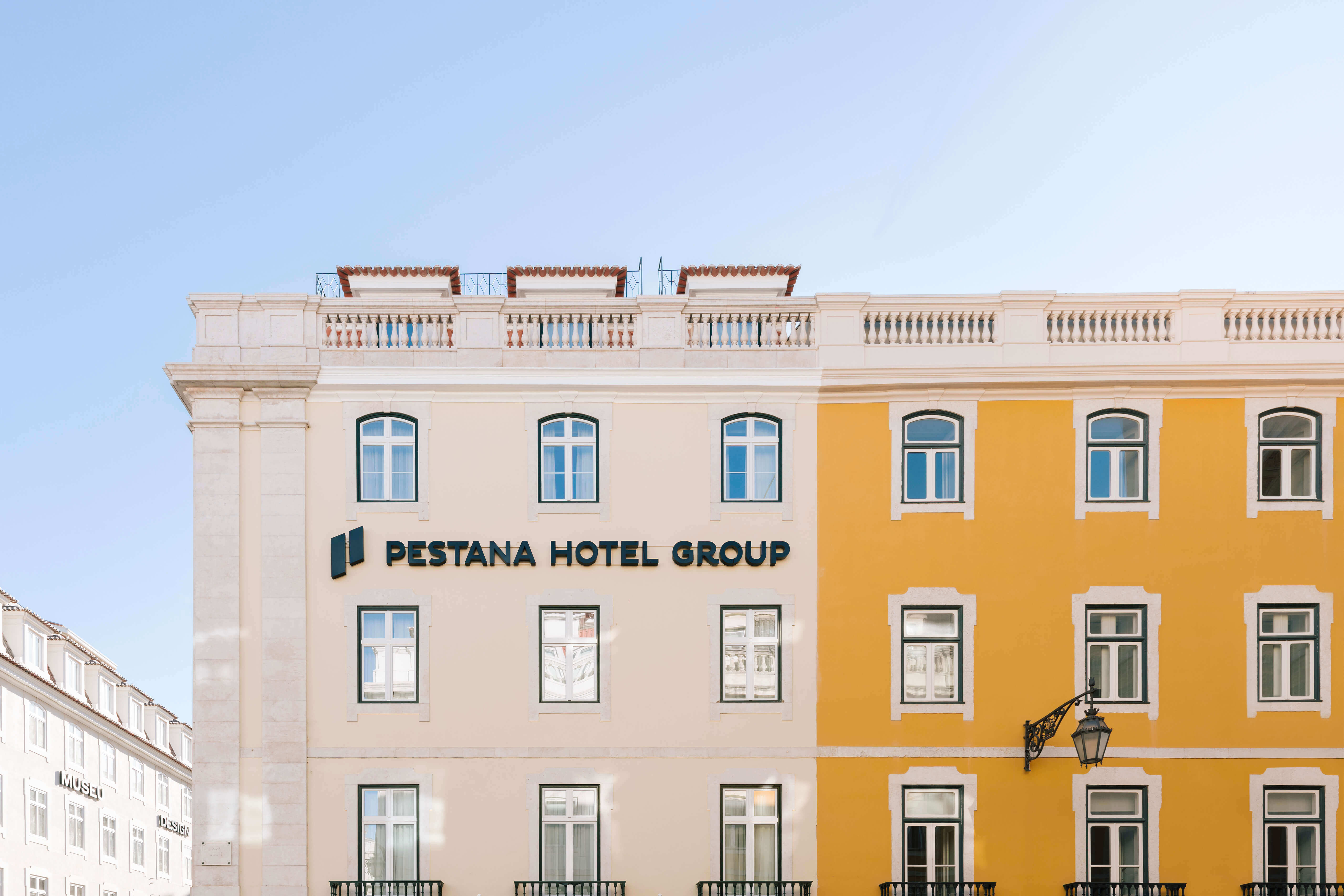 Lateral del edificio blanco y naranja del Pestana Rua Augusta Lisboa, con logotipo de Pestana Hotel Group