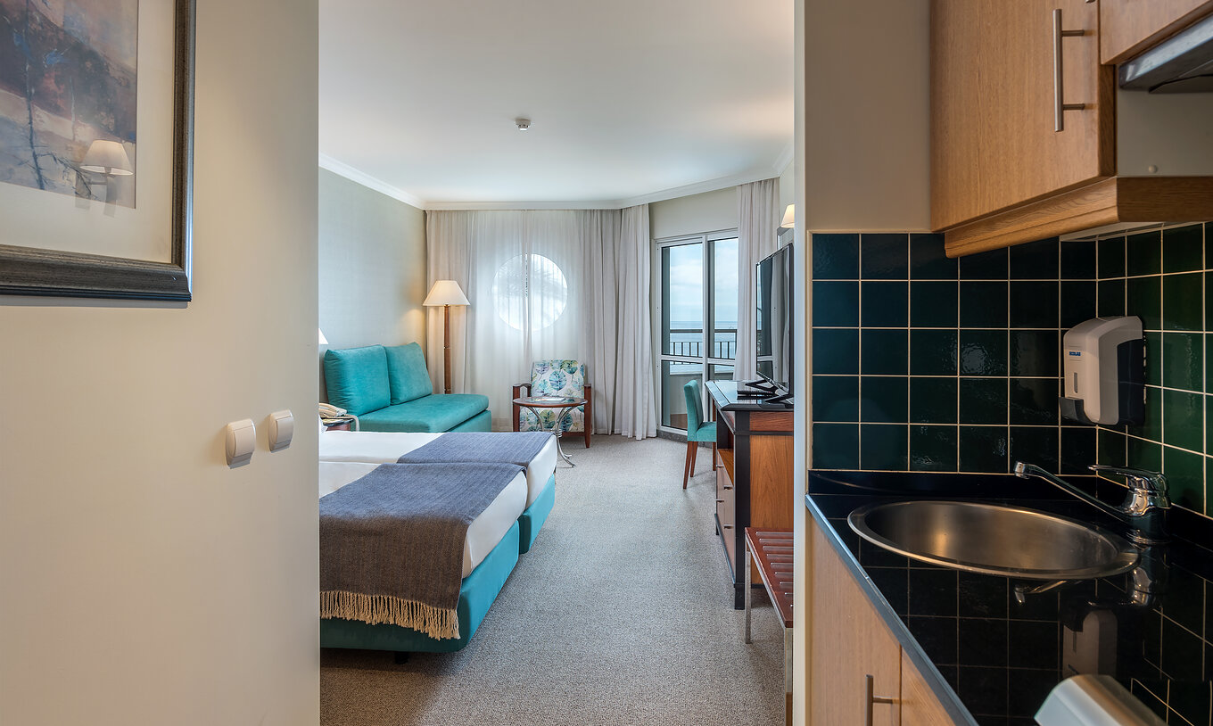 El cuarto Familiar del Pestana Grand tiene una cocina con lavamanos, con dos camas individuales y sofá