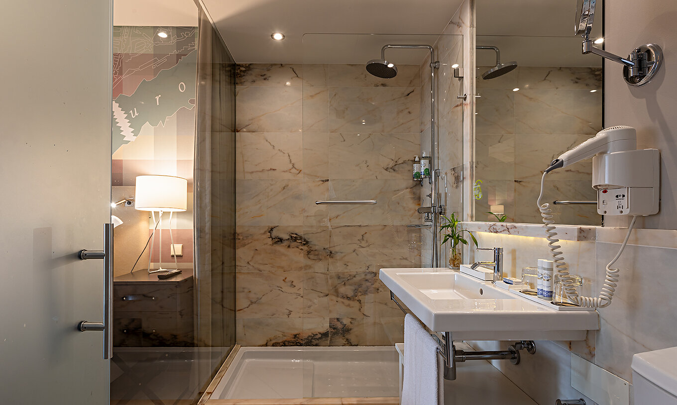 El Classic del Pestana Vintage Porto tiene un baño con un lavabo y una ducha rodeada de paredes de mármol