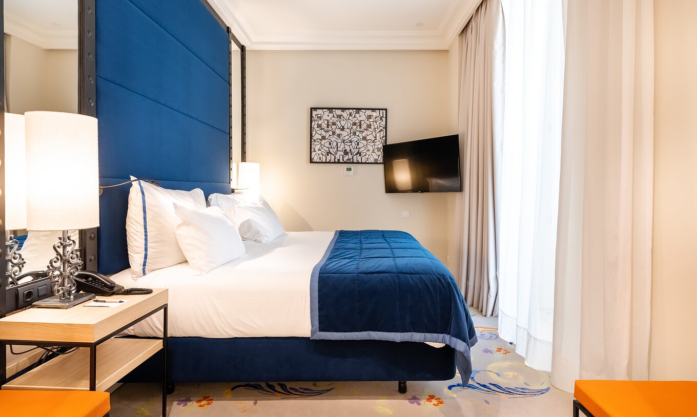 La habitación Superior del Pestana Plaza Mayor Madrid tiene una cama doble, un cabecero azul, una televisión y espejos