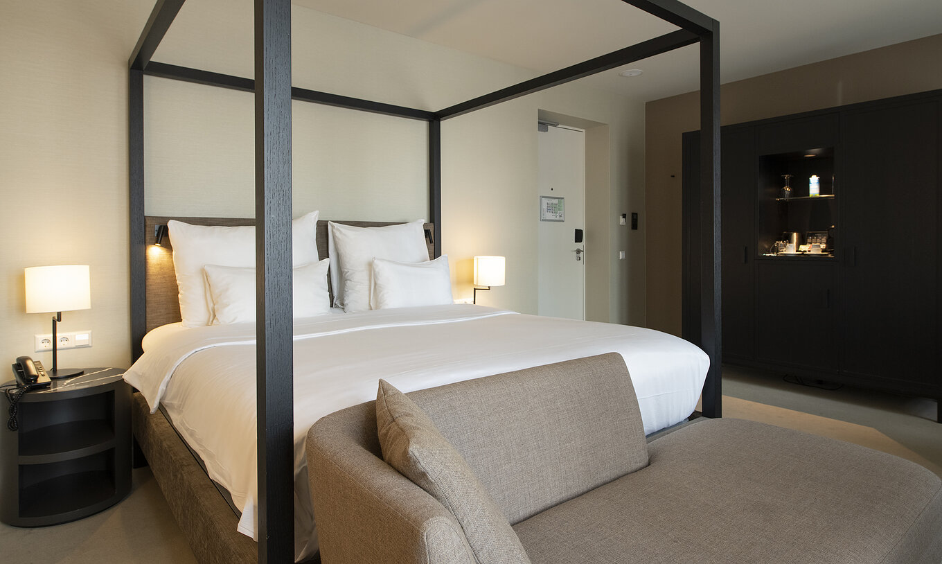 El cuarto Premium Deluxe del Pestana Amsterdam Riverside tiene una cama con dosel, mesa de noche, y un sofá