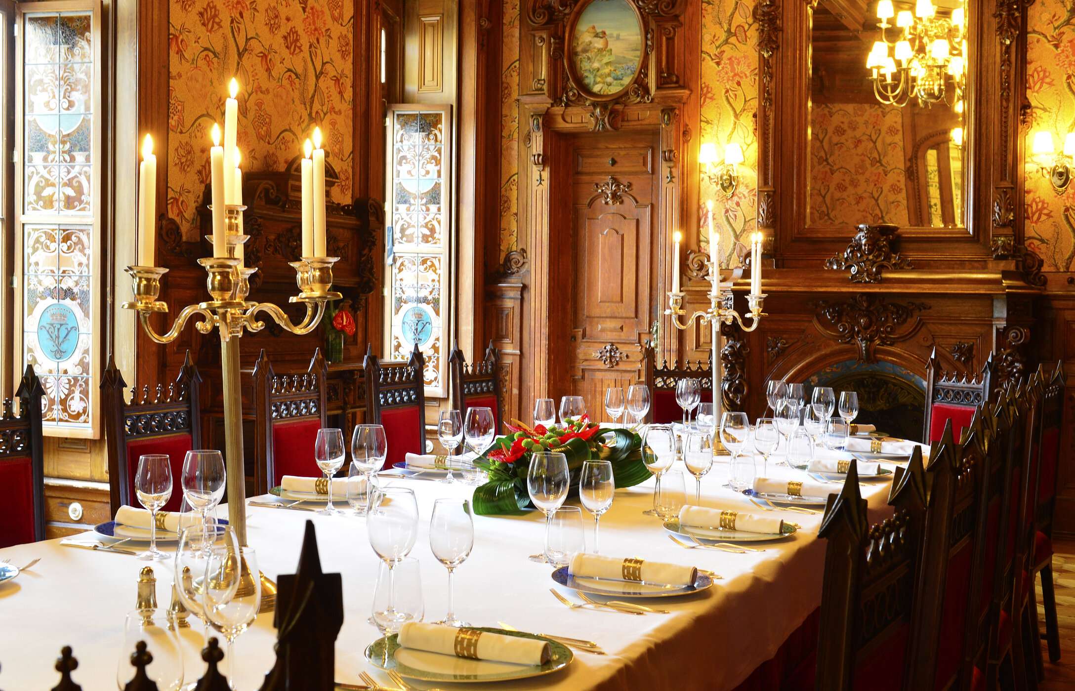 Boda en una sala imponente con decoración elegante, con una mesa larga con arreglos florales y paredes de madera tallada