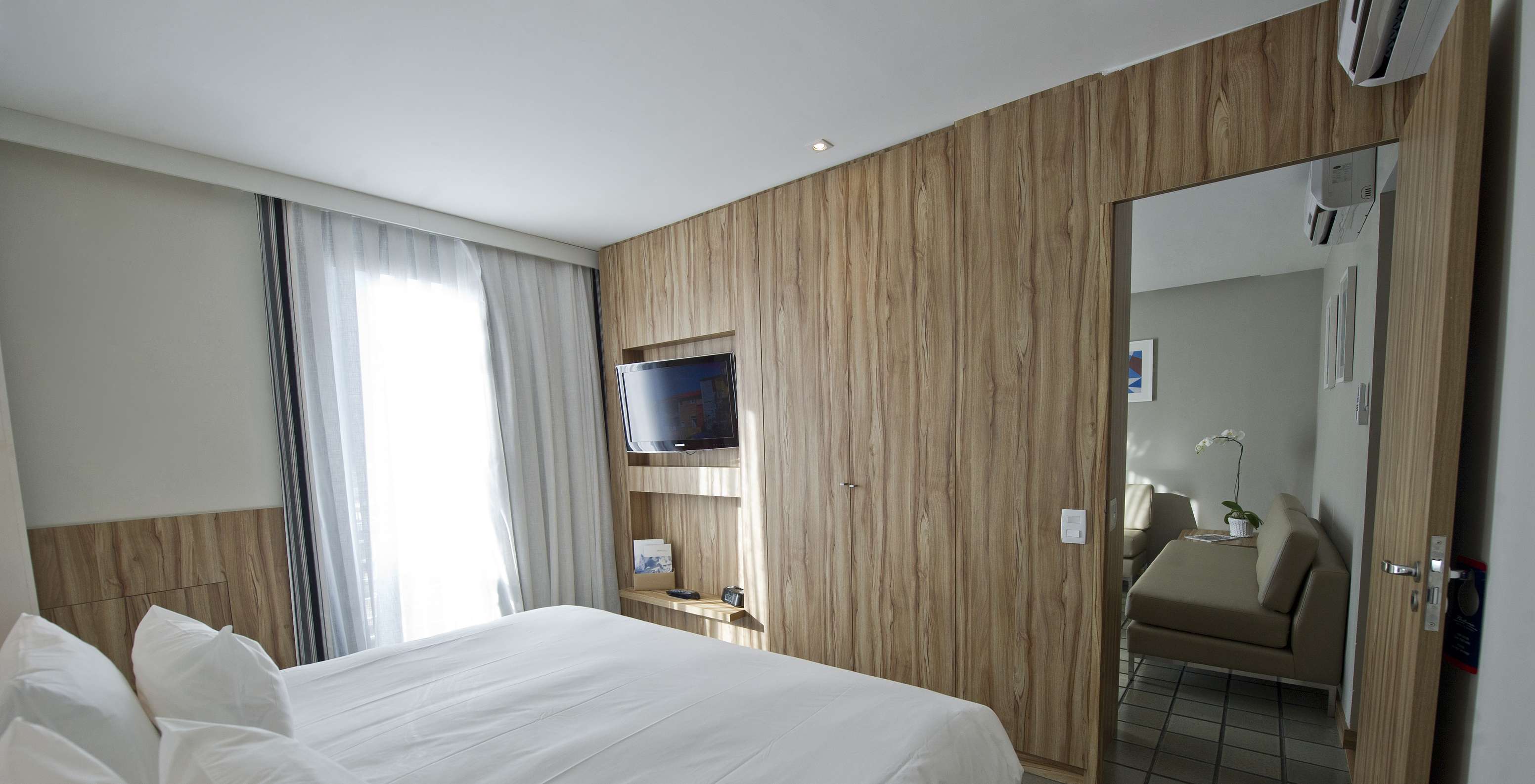 La Suite Standard du Pestana Rio Atlântica a une chambre avec lit double et télévision, et un salon avec canapés et climatisation