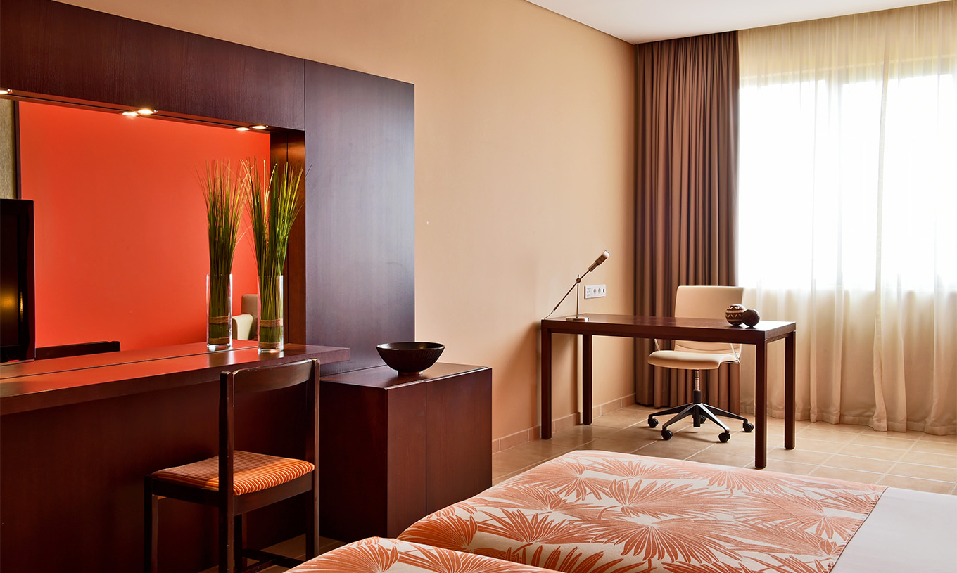 Le Chambre Classic Vue Mer du Pestana Tropico comprend un bureau avec lampe et une chaise, lit et un miroir