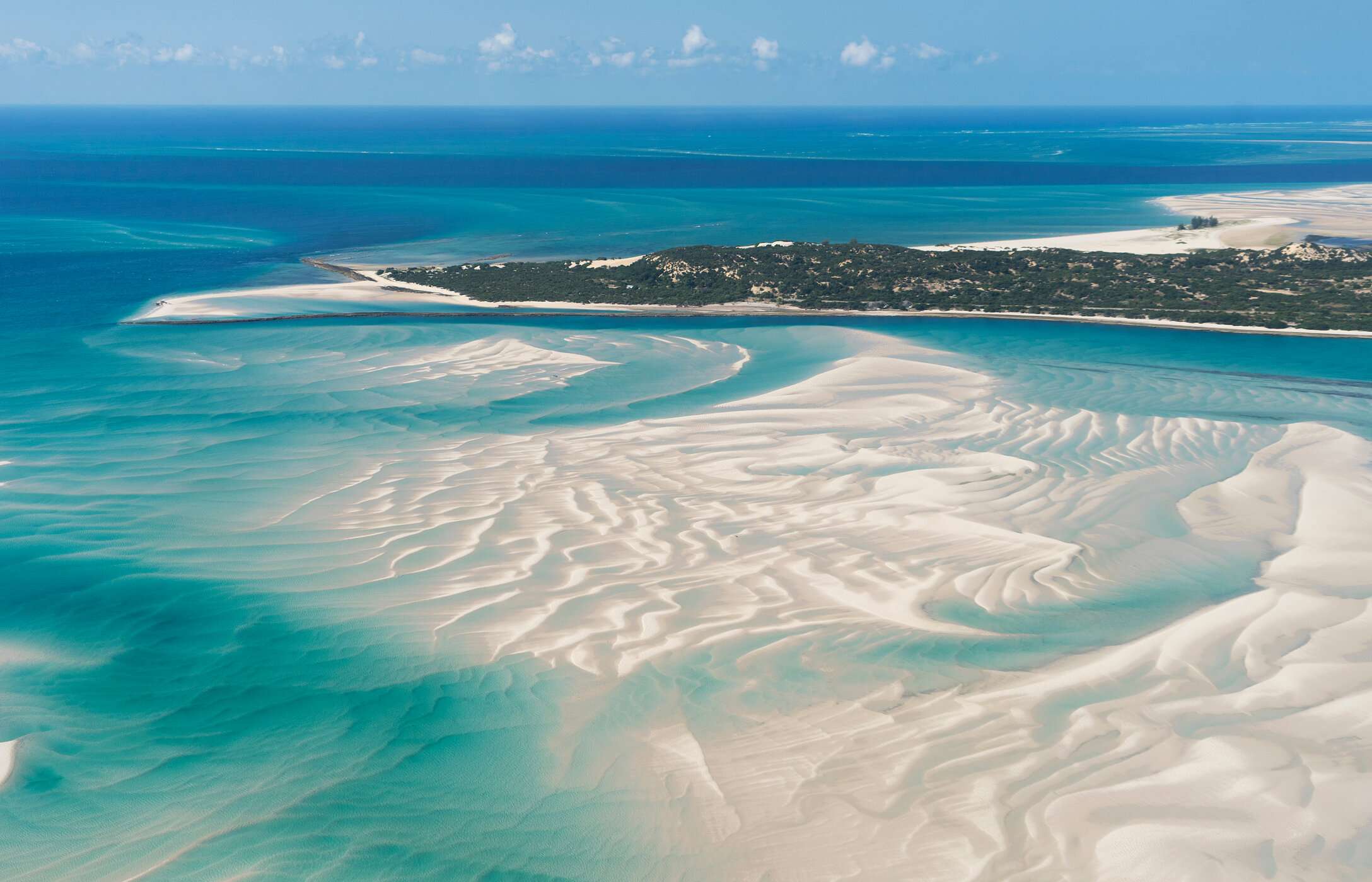Vue aérienne de l'île de Vilankulo, Mozambique, avec des eaux cristallines, des bancs de sable et de la végétation.