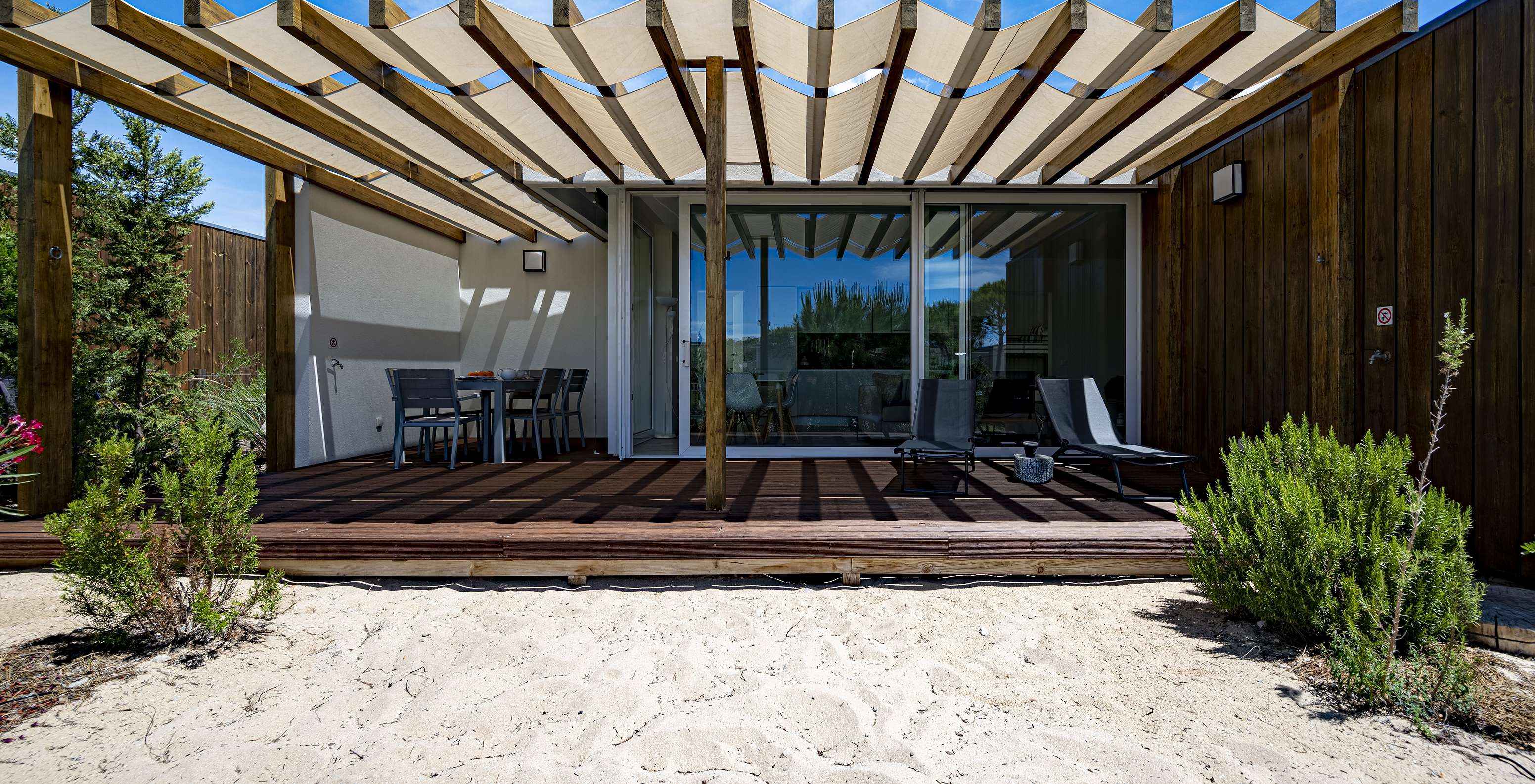 La Green Villa du Pestana Tróia Eco Resort a une terrasse avec deux chaises longues et une table avec chaises