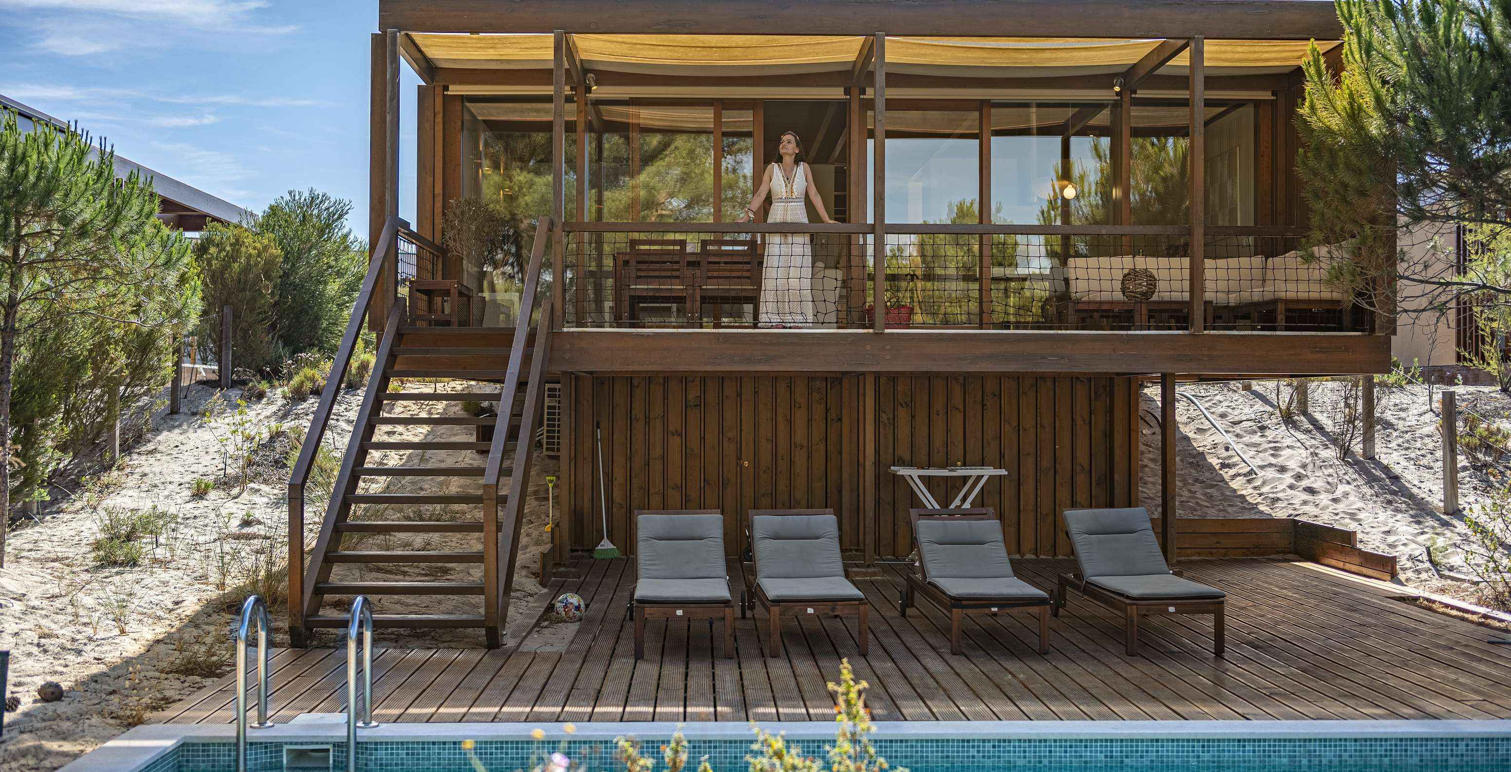 La Tree Villa avec piscine privée du Pestana Tróia Eco Resort a une femme sur la terrasse qui donne accès à la piscine