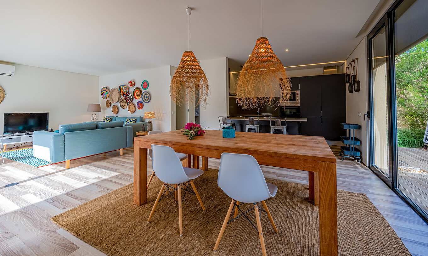 Les Pine Villas du Pestana Tróia Eco Resort ont une salle avec une table en bois, lampes et une cuisine