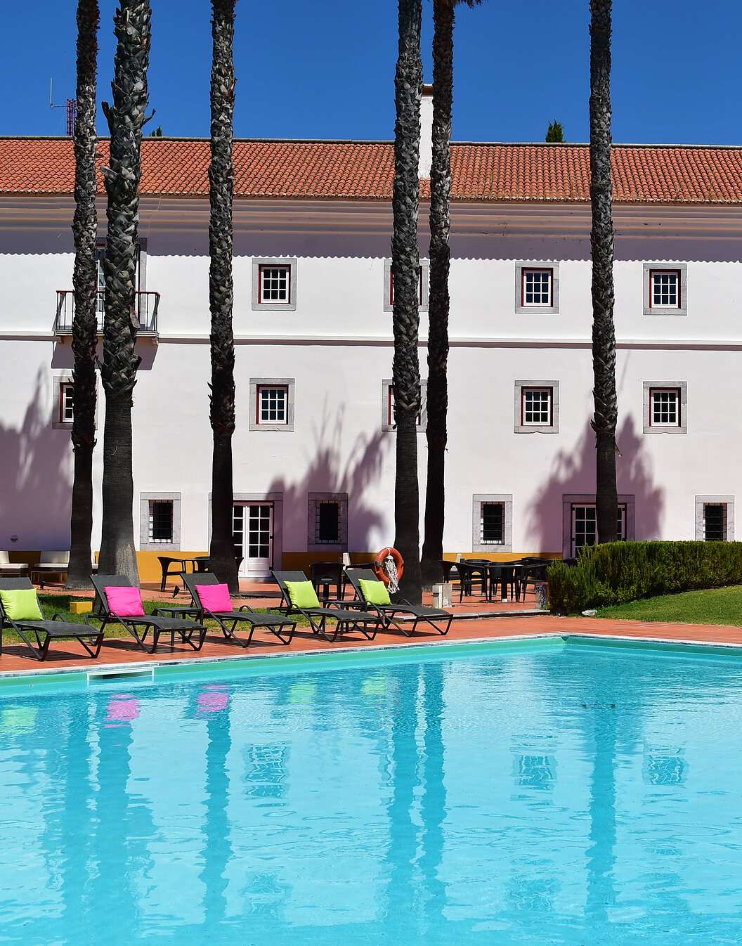 Piscine extérieure de la Pousada Convento Beja, un hôtel historique dans l'Alentejo, avec plusieurs transats avec coussins