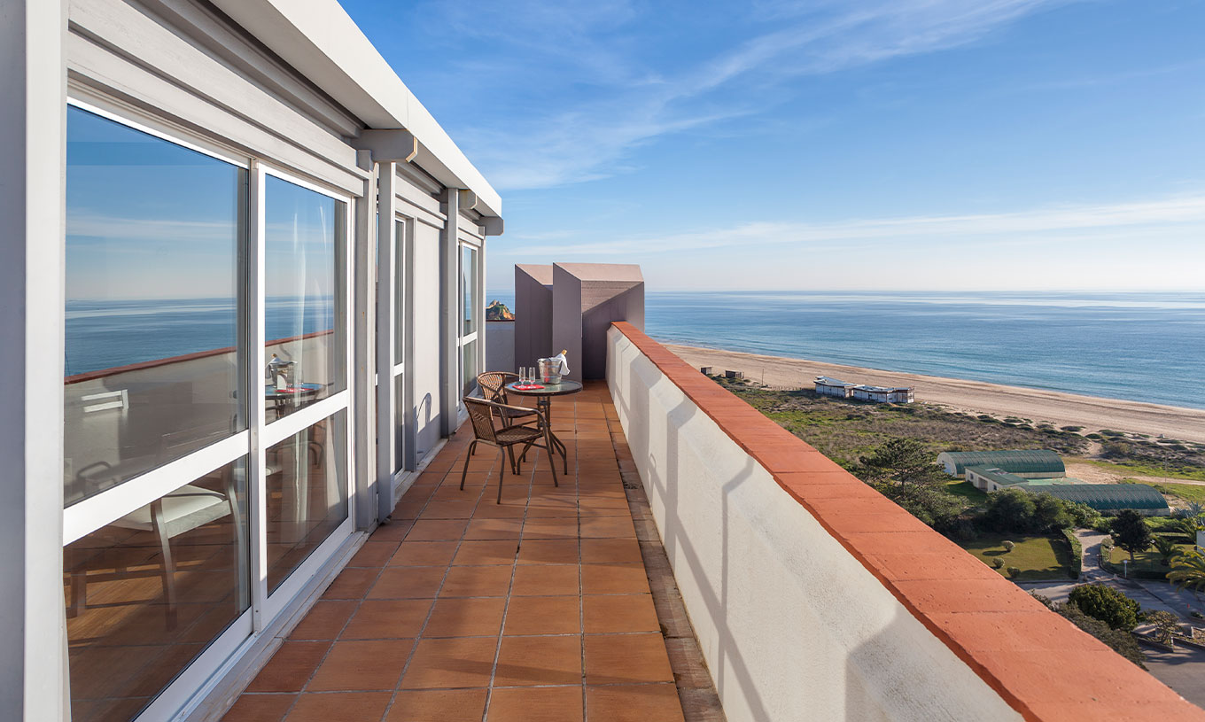 L'Appartement T1 Vue Mer du Pestana Alvor Atlântico a un balcon avec table et deux chaises, avec vue sur la plage