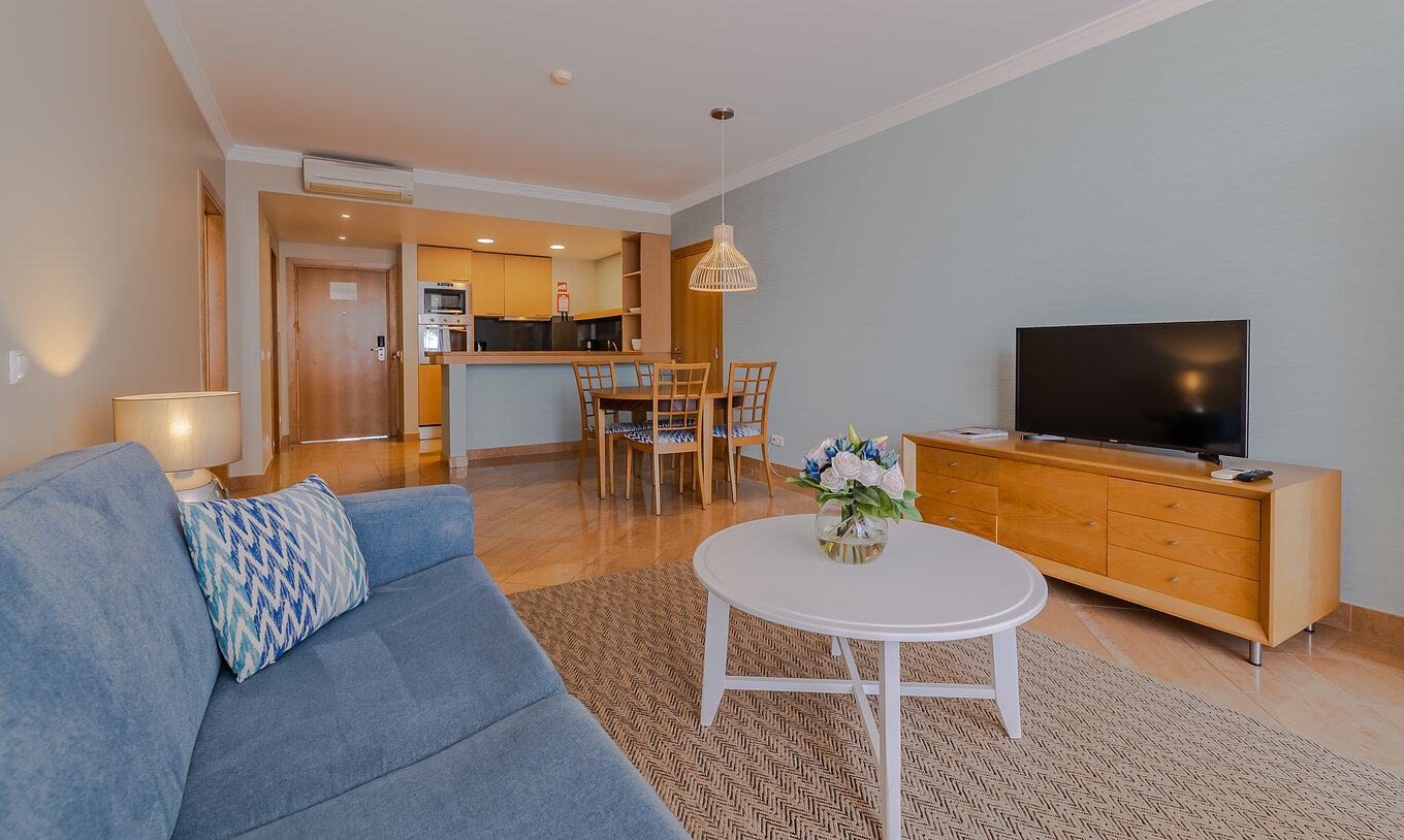 Le T1 - 1 Chambre du Pestana Alvor Park a salon avec canapé, table à manger et kitchenette avec comptoir