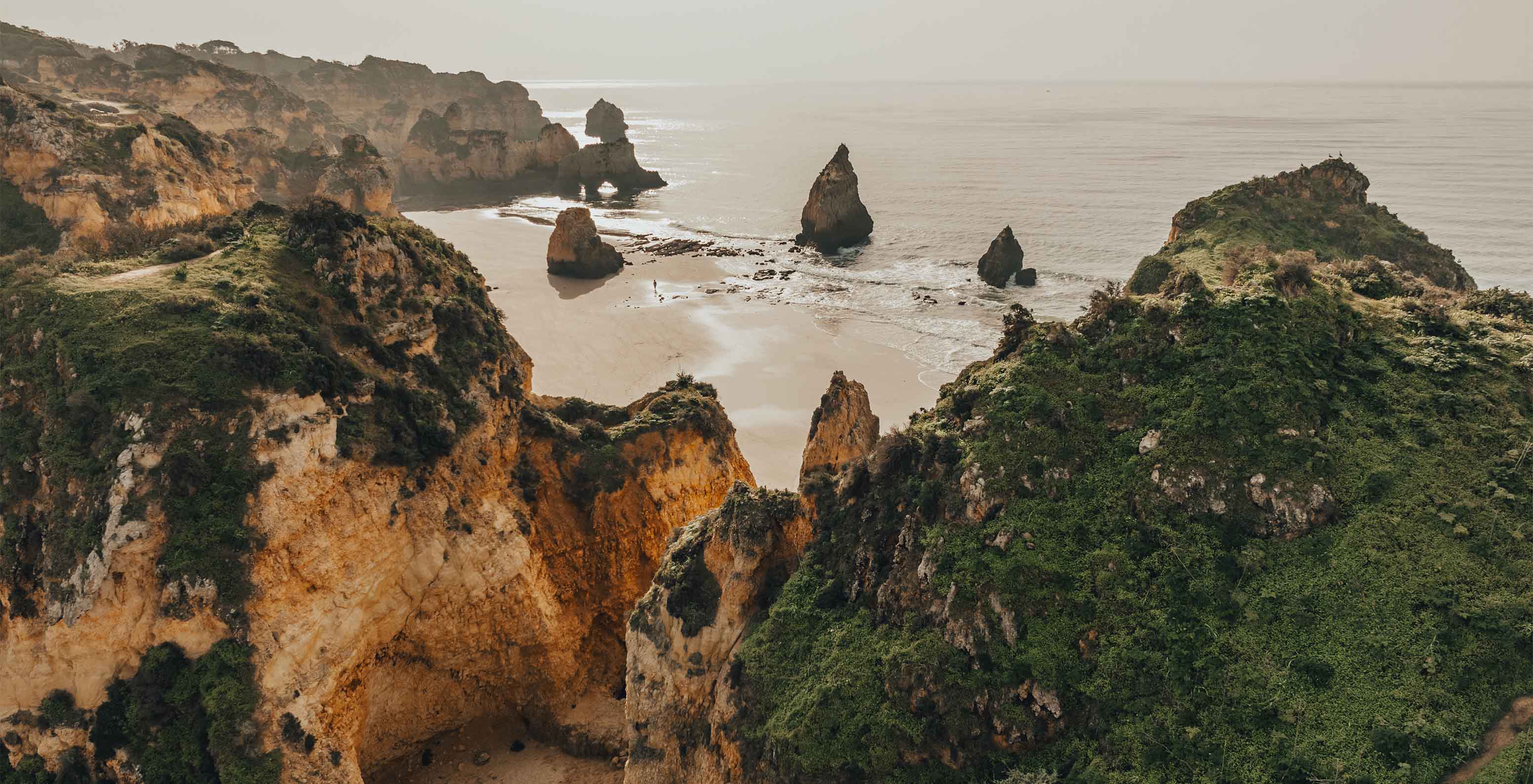 Plage des Trois Frères avec formations rocheuses, végétation et brouillard