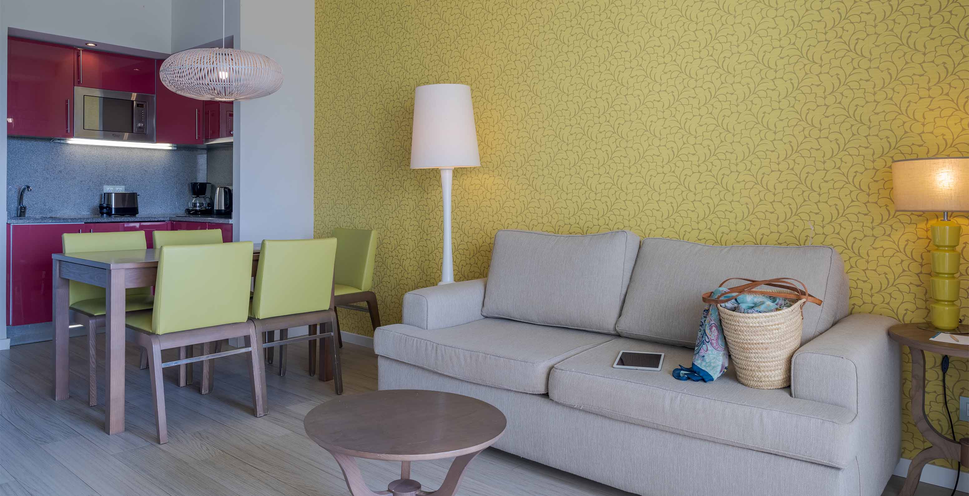 La Suite T1 Vue Jardin du Pestana Alvor Praia a une table à manger avec cinq chaises vertes et un canapé avec table d'appoint