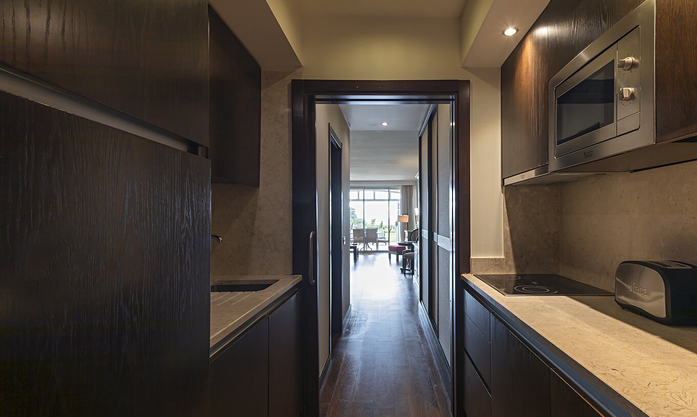 Le Cliff Family du Pestana Alvor Praia a une cuisine équipée en bois foncé et pierre, avec cuisinière et micro-ondes