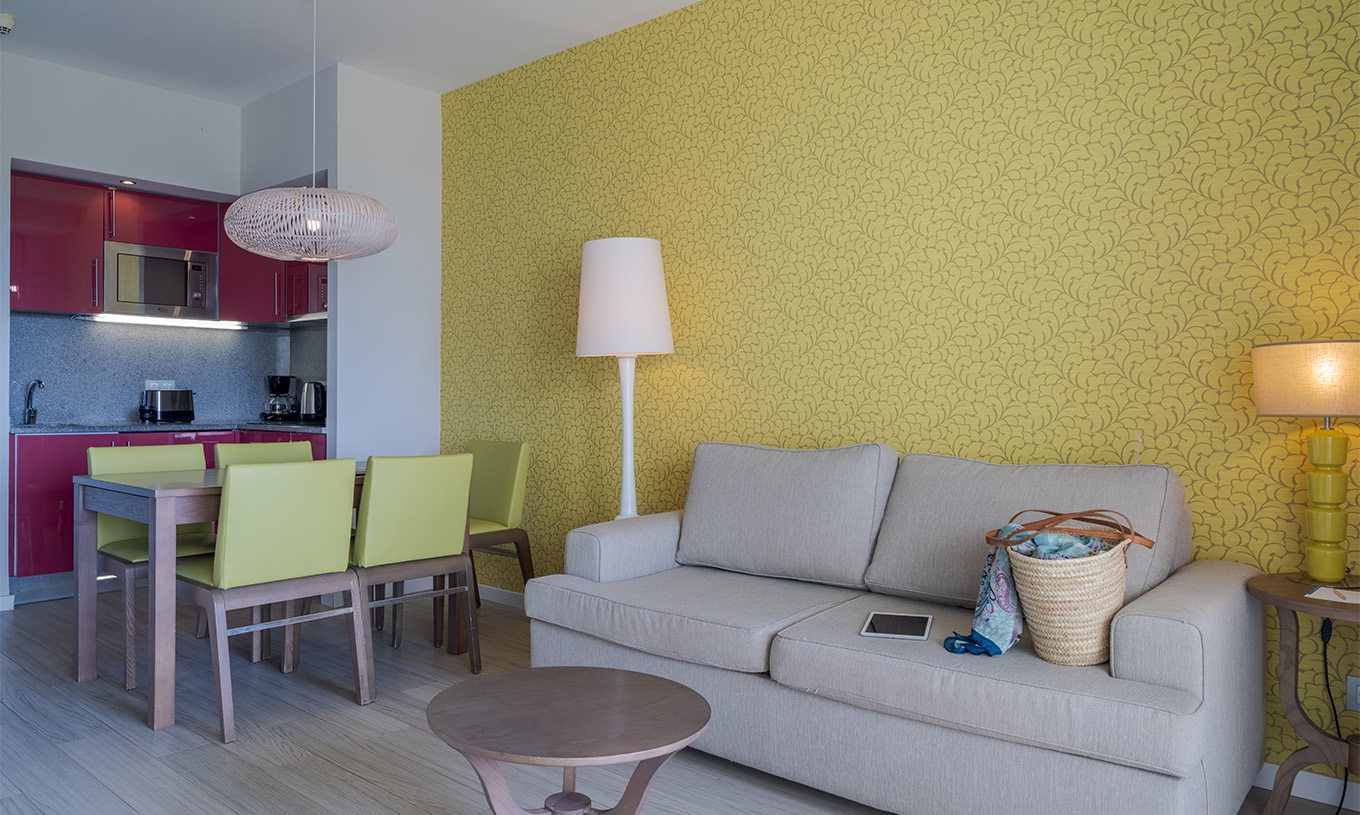 La Suite T1 Vue Jardin du Pestana Alvor Praia a une table à manger avec cinq chaises vertes et un canapé avec table d'appoint