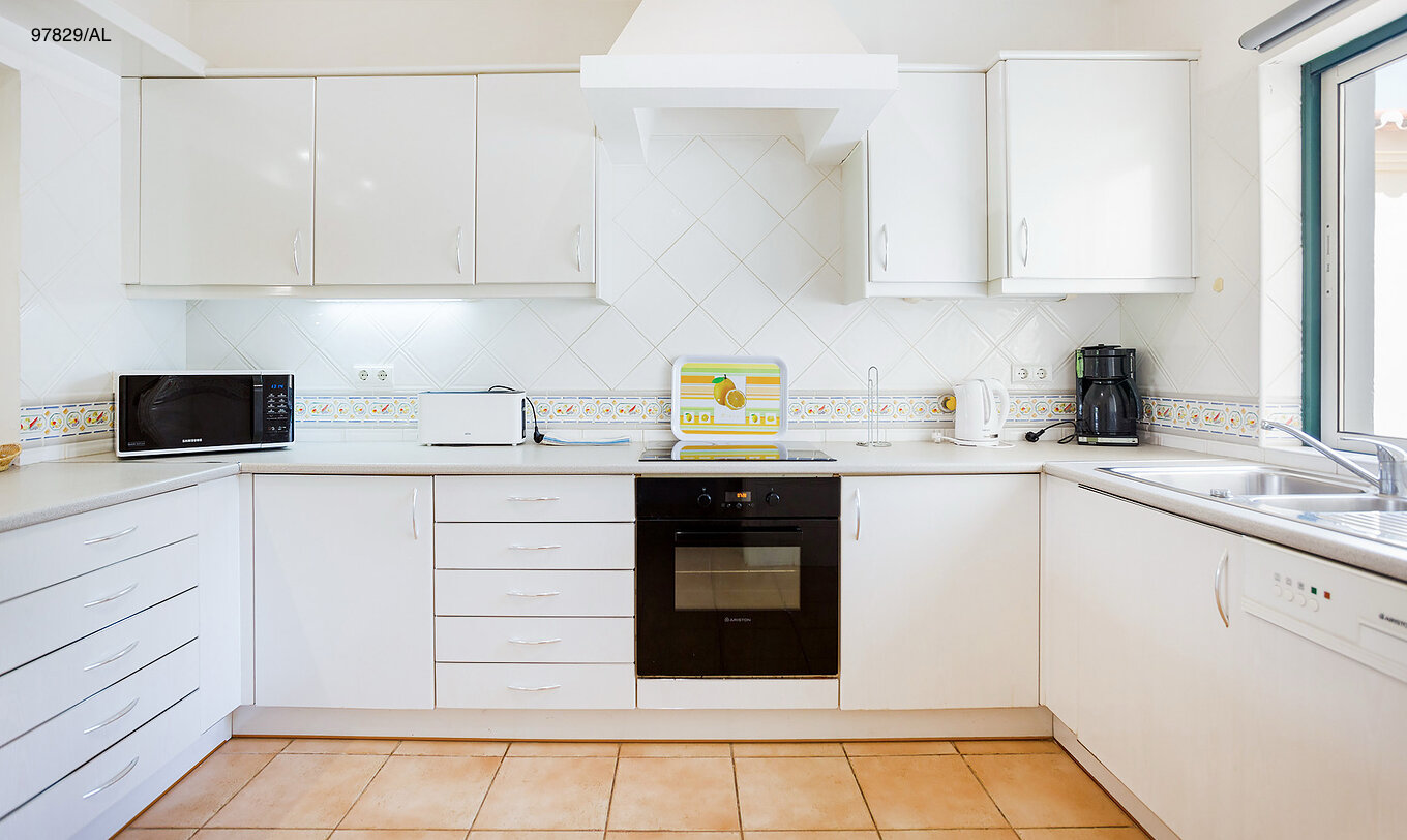 L'appartement Pestana Carvoeiro Golf T2 Standard dispose d'une cuisine avec des armoires blanches et un plan de travail