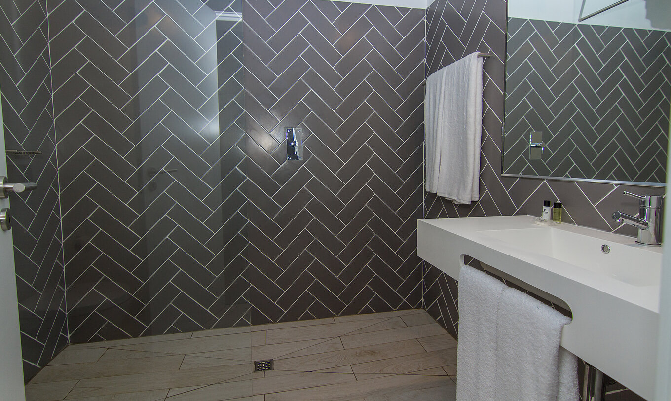 Le Studio du Pestana Gramacho Residences a une salle de bain avec douche à l’italienne, lavabo, miroir et serviettes