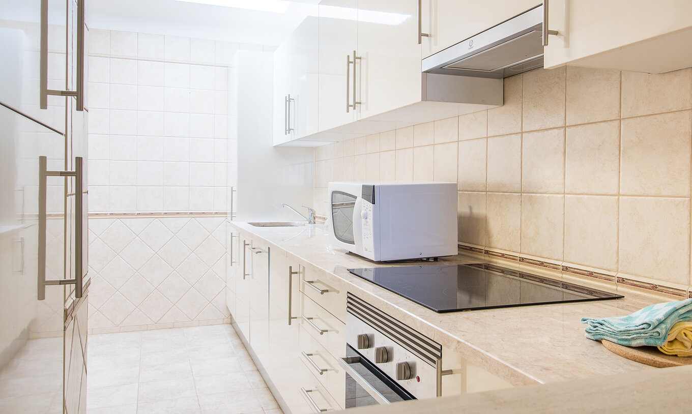 L’appartement deux chambres du Pestana Gramacho a une cuisine simple avec électroménager et déco neutre
