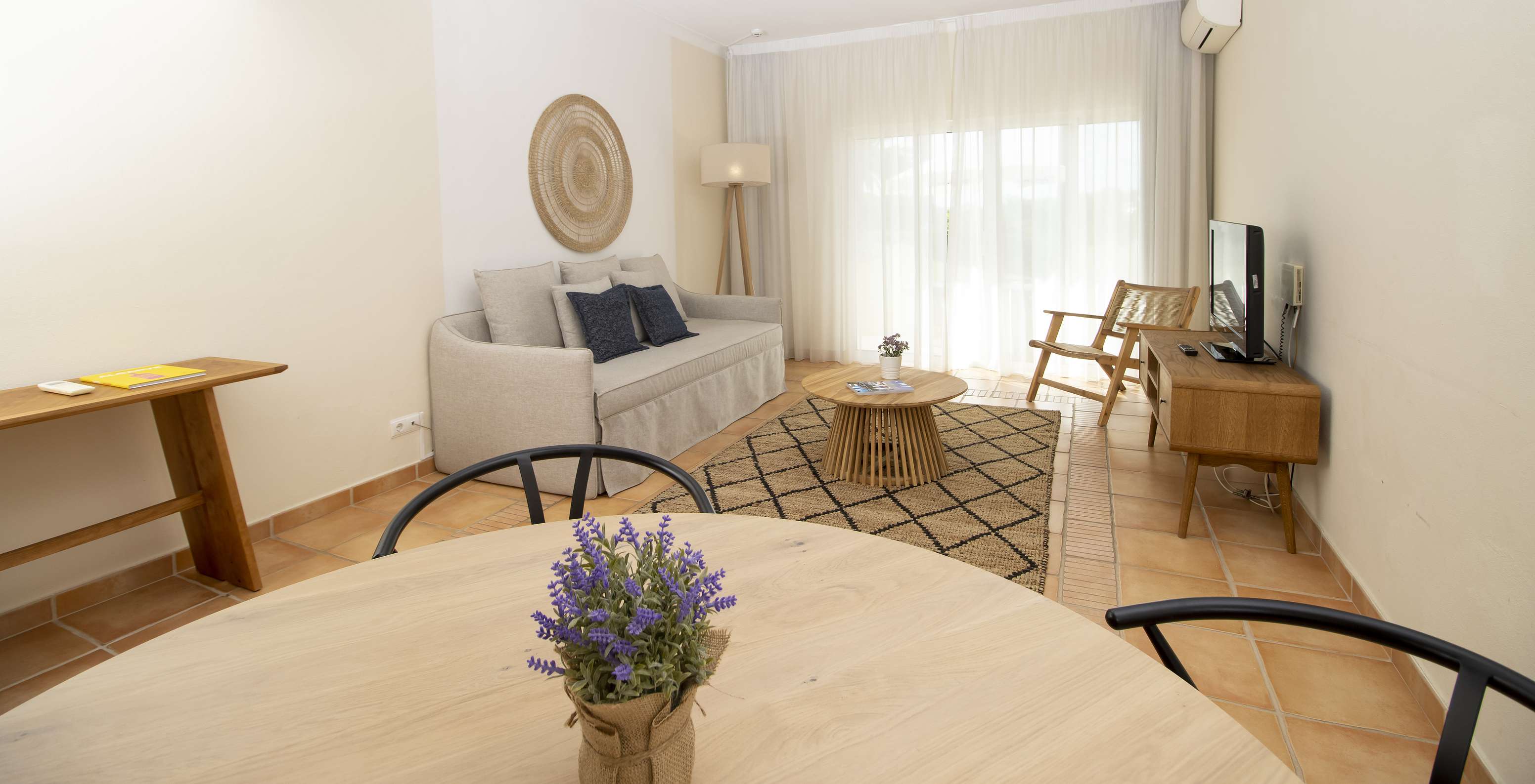 L'Appartement T2 Supérieur du Pestana Palm Gardens a un salon avec une table ronde, canapé et fenêtre vers le jardin