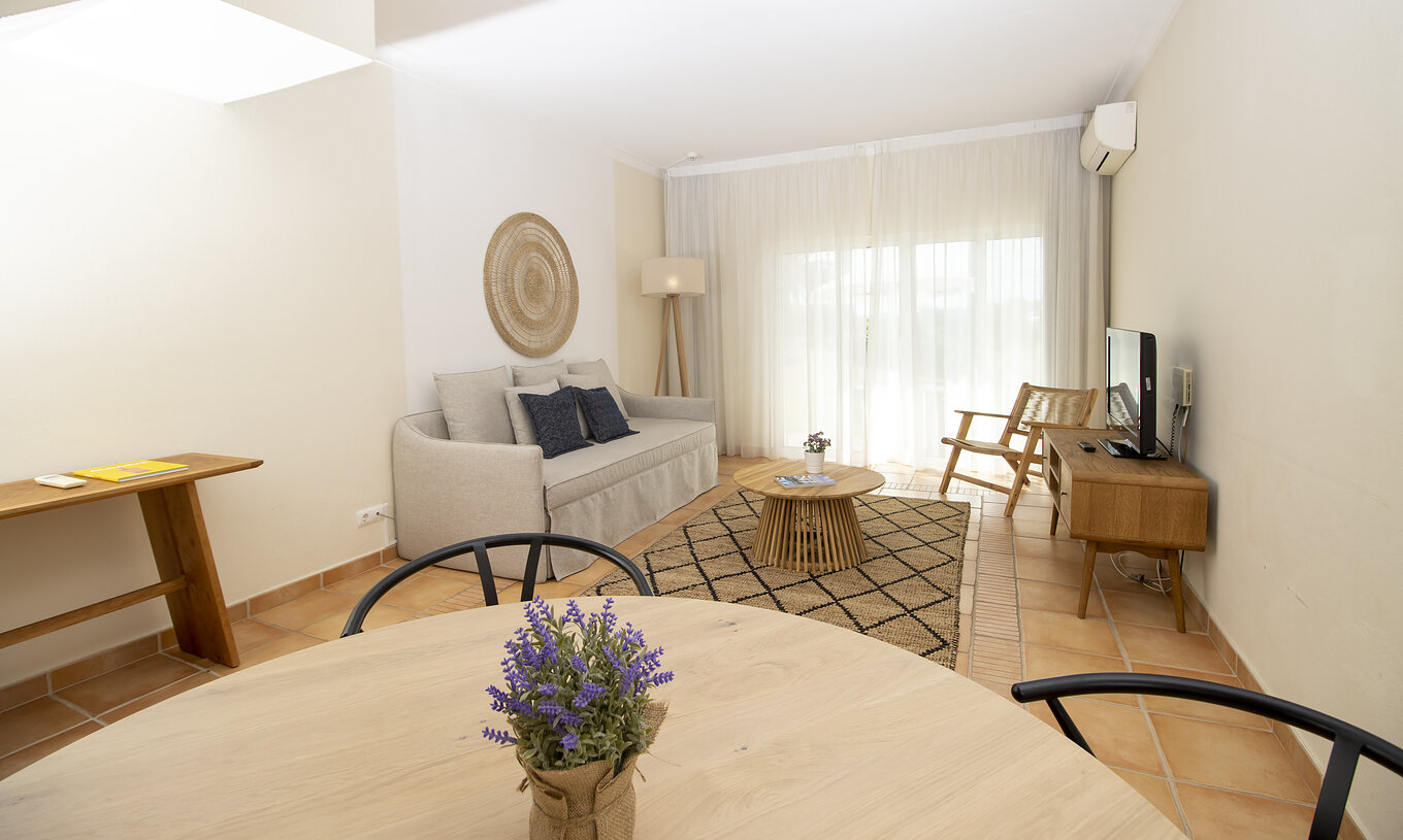 L'Appartement T2 Supérieur du Pestana Palm Gardens a un salon avec une table ronde, canapé et fenêtre vers le jardin