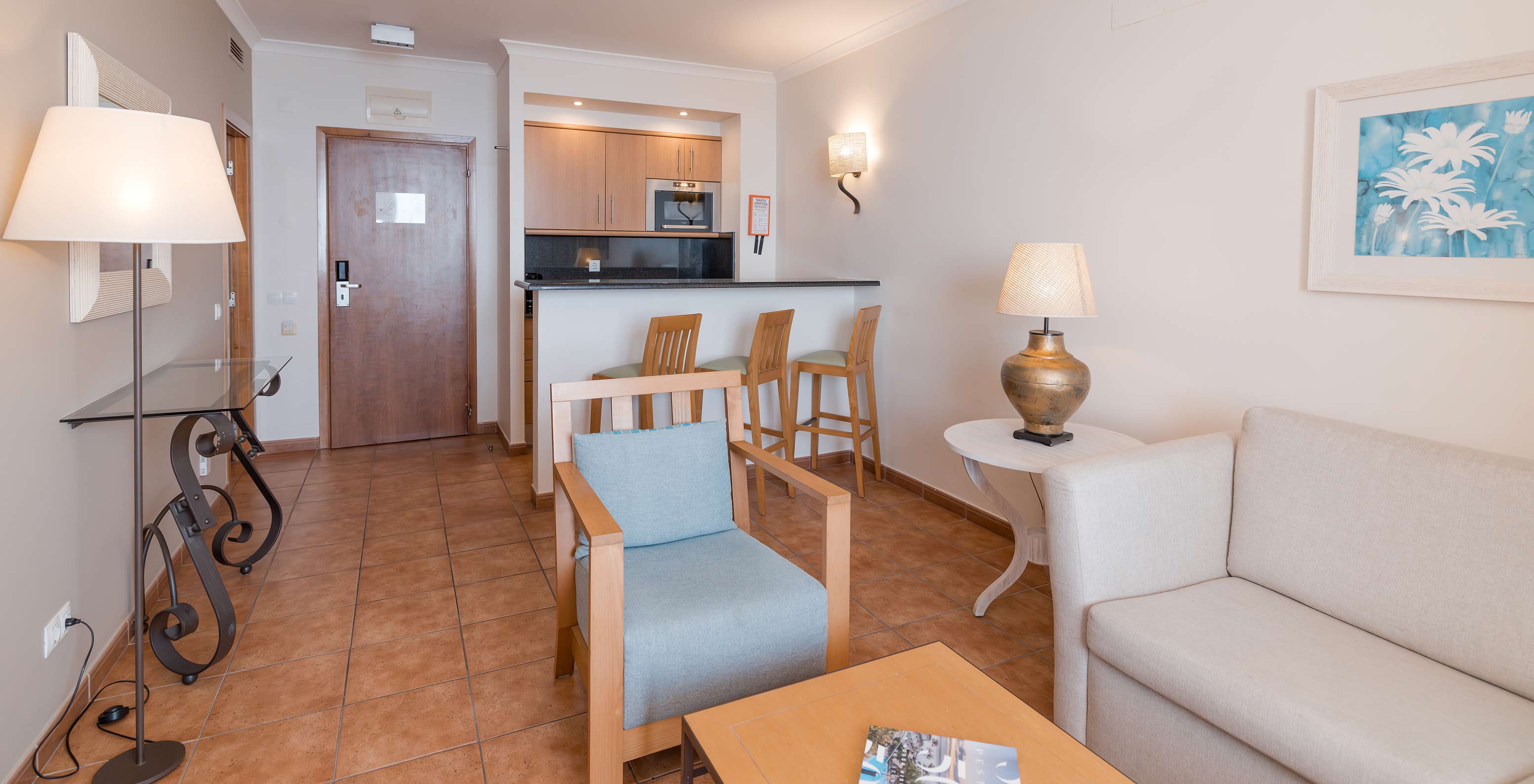 La Suite Vue Mer du Pestana Viking a un salon avec canapé, fauteuils et petite cuisine avec micro-ondes