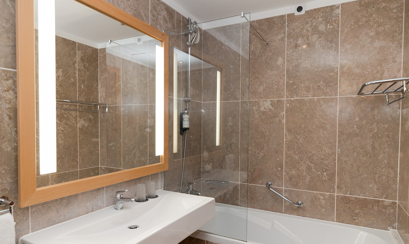 Le Deluxe Vue Mer du Pestana Viking a une salle de bain avec lavabo, grand miroir et baignoire avec douche