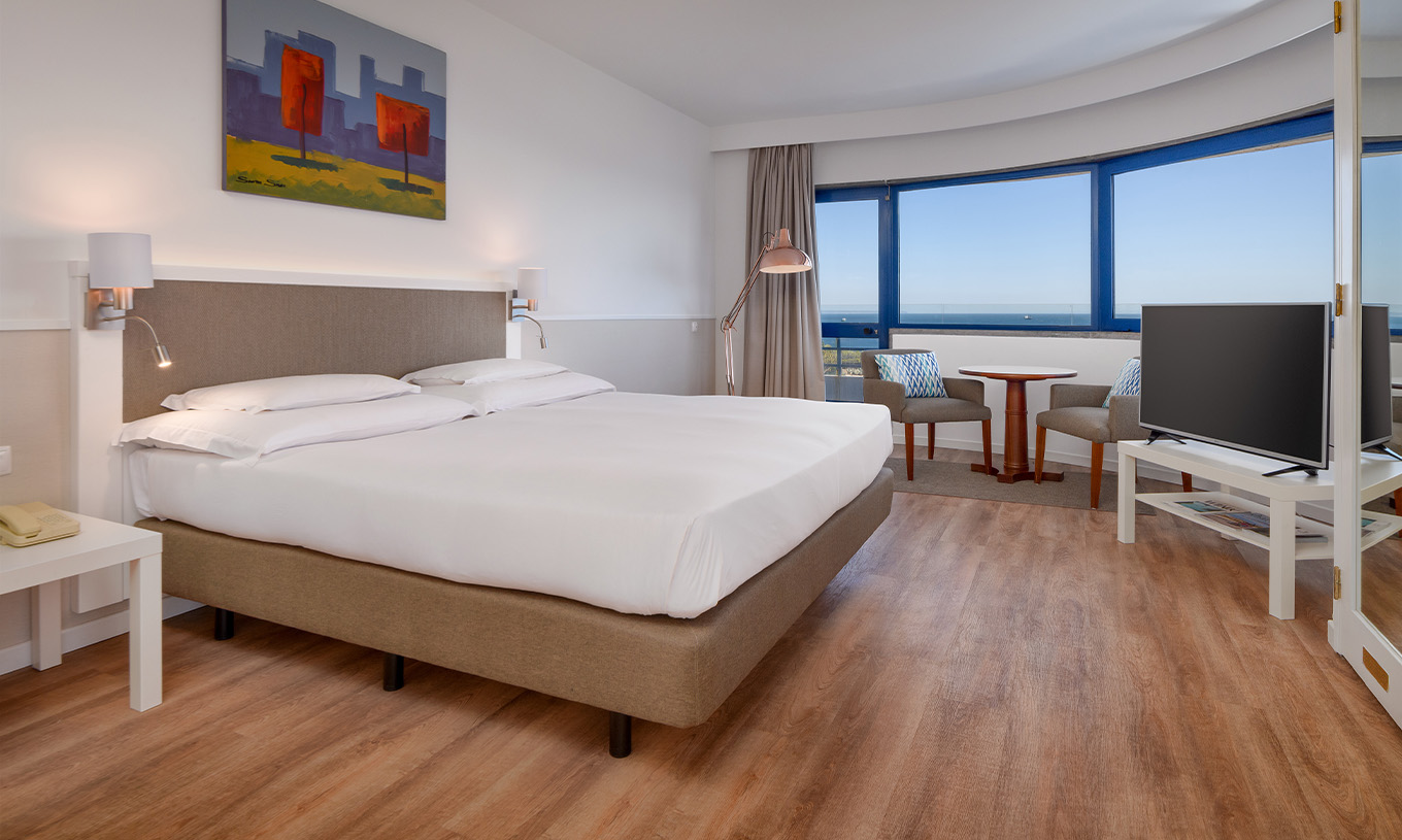 La Suite Deluxe Vue Mer du Pestana Cascais a un lit double, télévision, et un tableau peint au mur