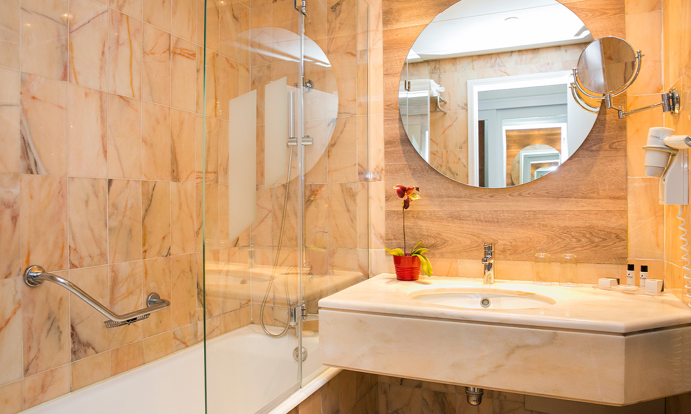 La Suite Deluxe du Pestana Cascais a une salle de bains avec miroir, lavabo et baignoire avec douche