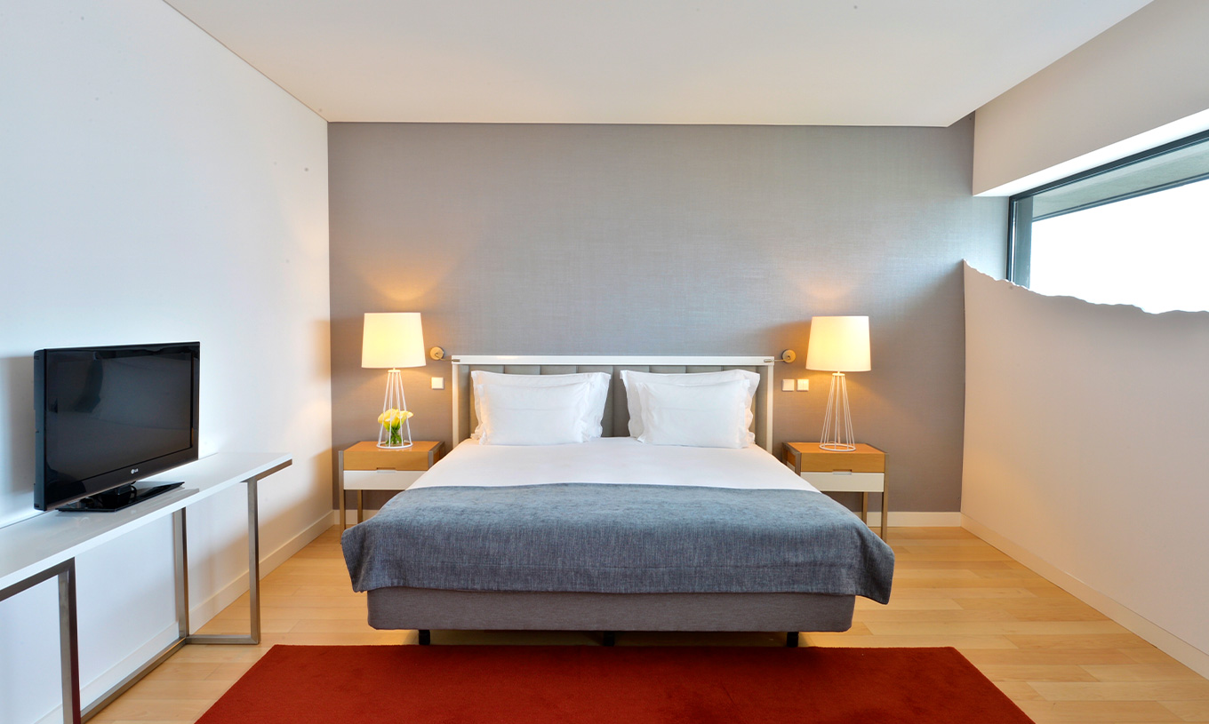 La Chambre Double Superior du Pestana Cidadela Cascais a un lit double, deux tables de chevet et un tapis rouge élégant