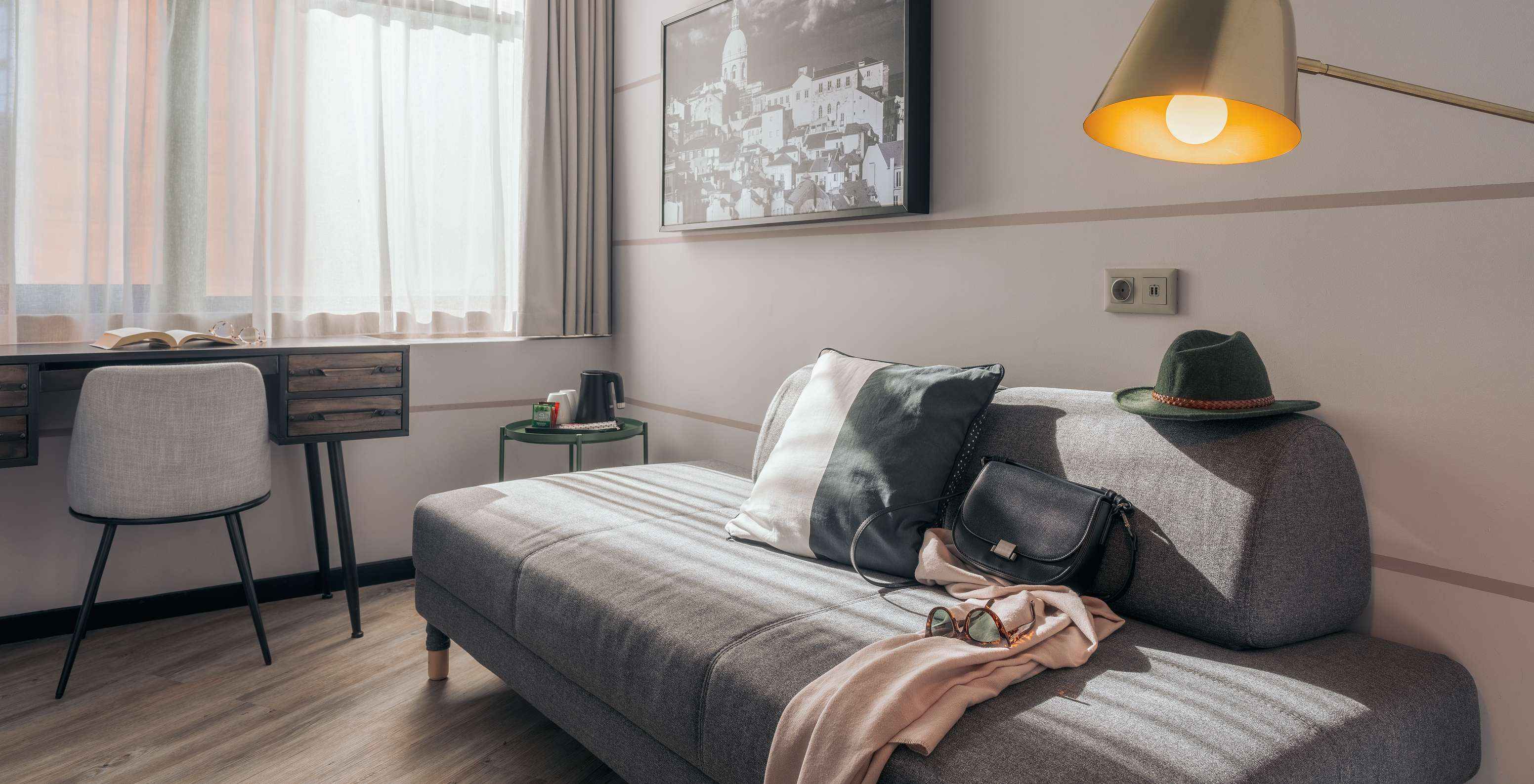 Le Double Supérieur du Pestana Lisboa Vintage a un canapé gris une bureau avec chaise une table d'appoint et un tableau