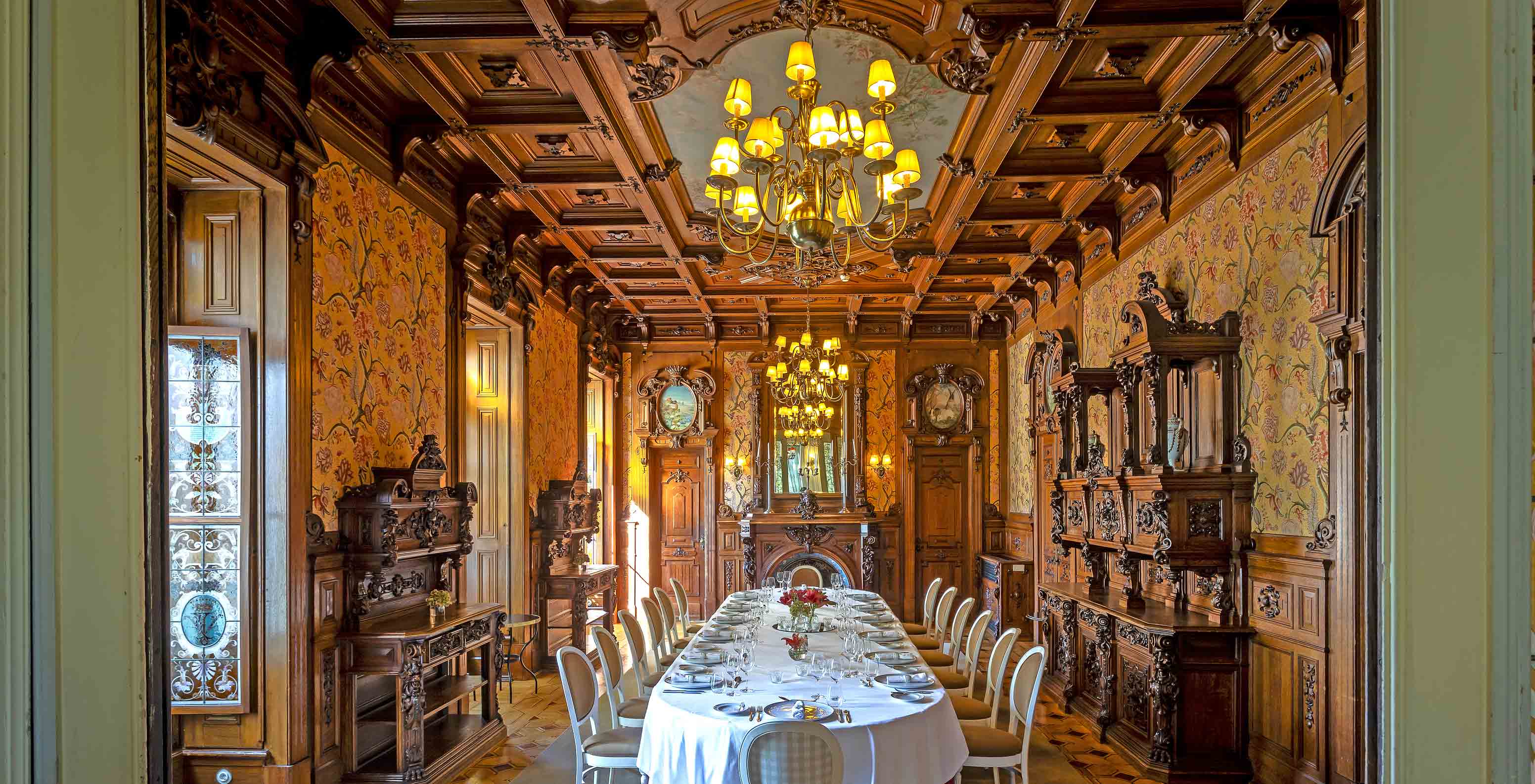 Le Pestana Palace Lisboa possède une salle à manger privée avec un plafond en bois, trois lustres et une table ovale