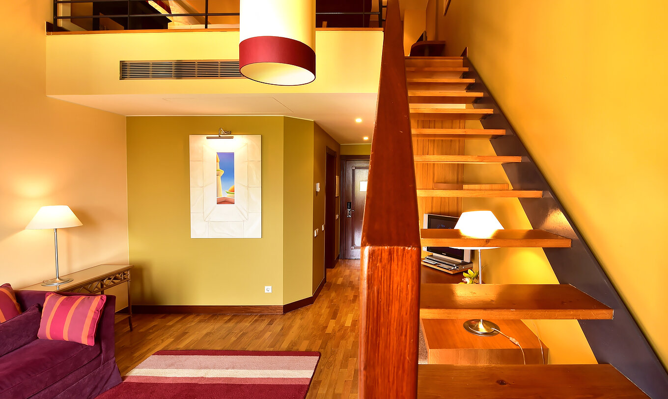 La Suite Mezzanine Jacuzzi du Pestana Sintra Golf a un canapé, des escaliers vers la mezzanine, un tableau et une lampe