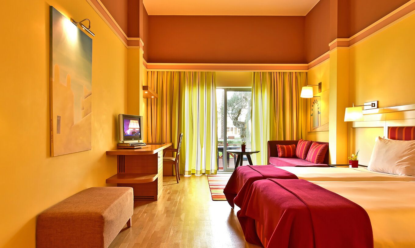 Le Duplo Superior du Pestana Sintra Golf a deux lits, une télévision, un canapé et une fenêtre avec vue jardin