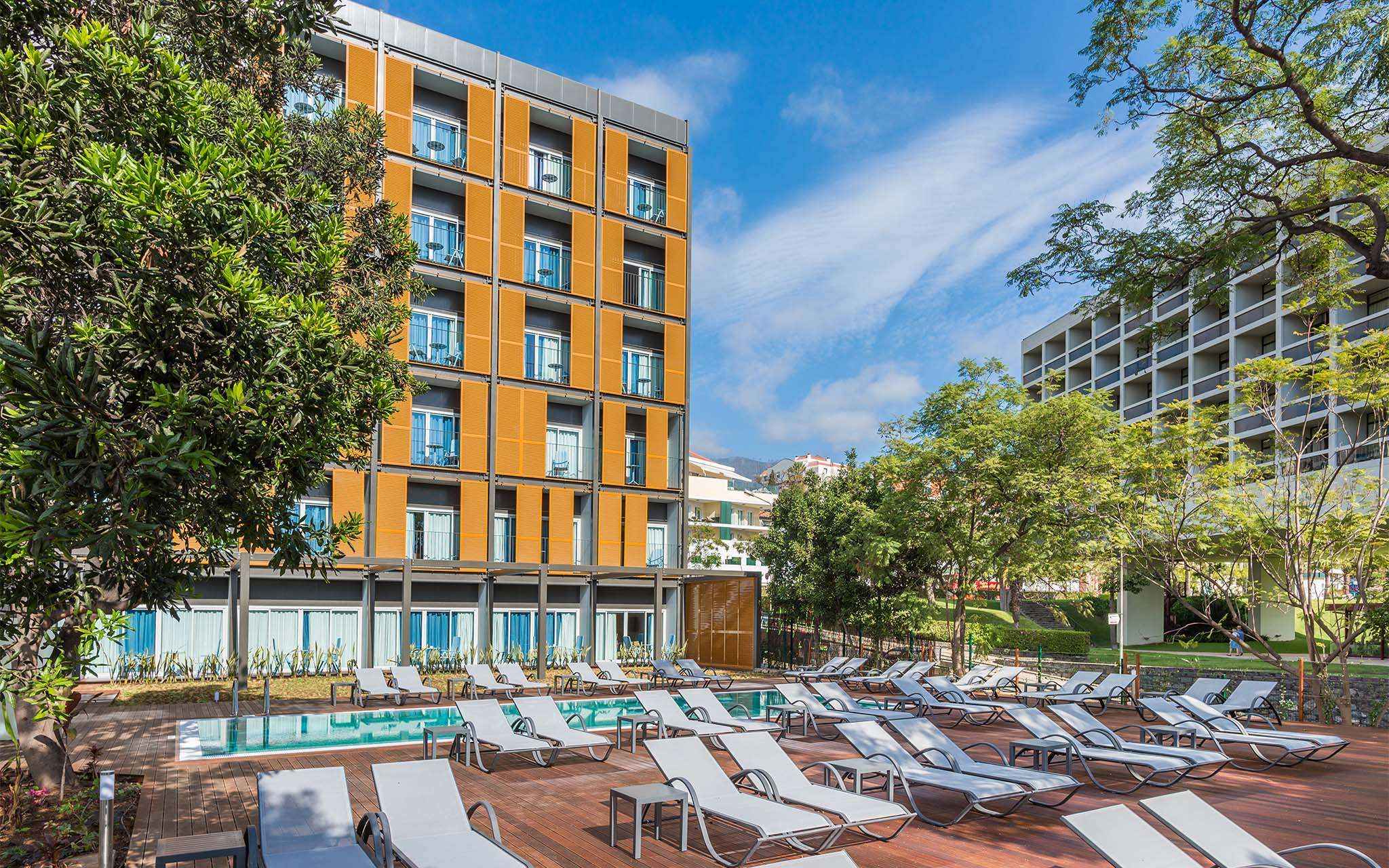 Vue extérieure des Pestana Casino Studios, avec appartements au centre, piscine et un bâtiment orange