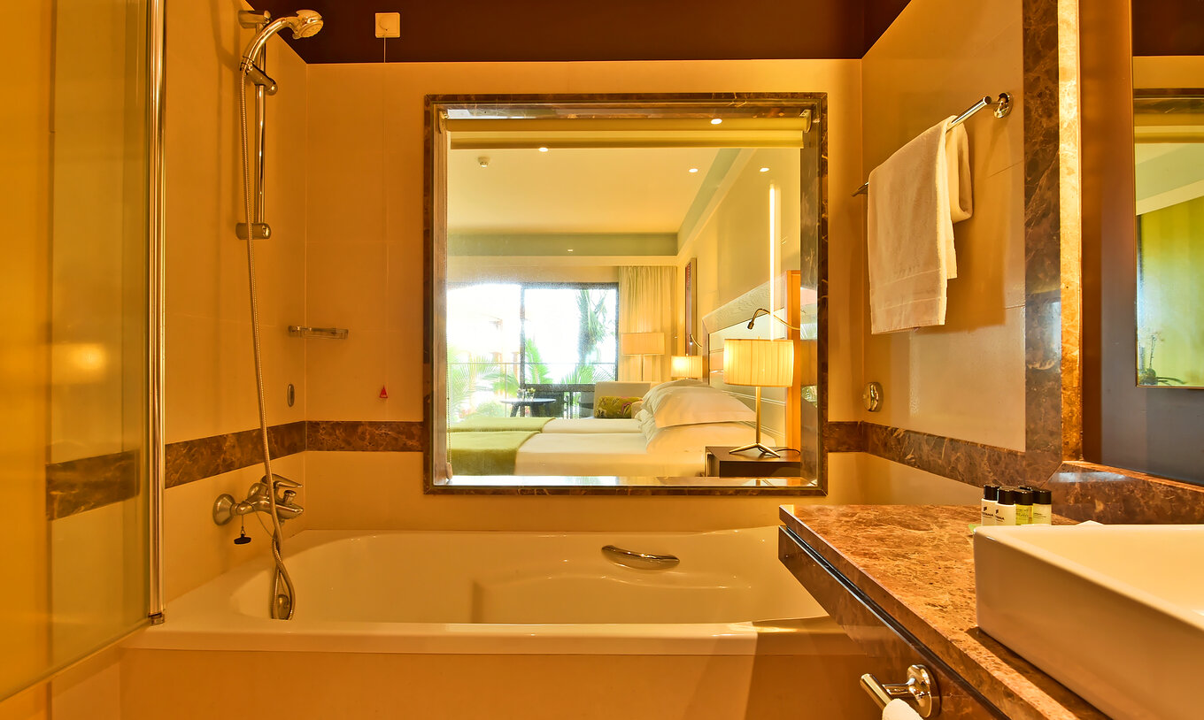 Le Supérieur du Pestana Promenade a une salle de bain avec baignoire, commodités et une vitre avec vue sur la chambre
