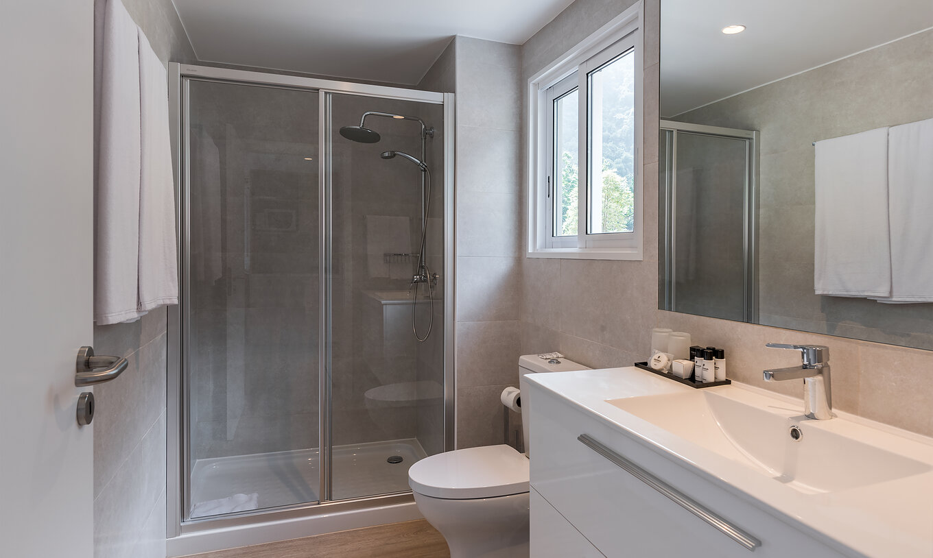 L'Étude - Vue mer du Pestana Quinta do Arco a salle de bain avec douche, toilettes, lavabo avec grand miroir et fenêtre