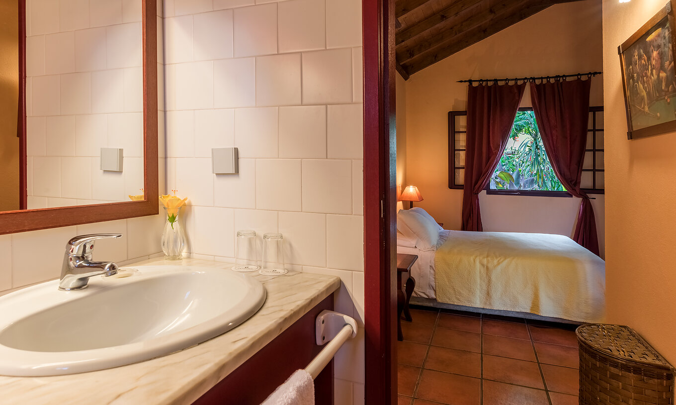 Les Villas du Pestana Quinta do Arco ont salle de bain avec lavabo et la porte ouverte pour la chambre avec lit double