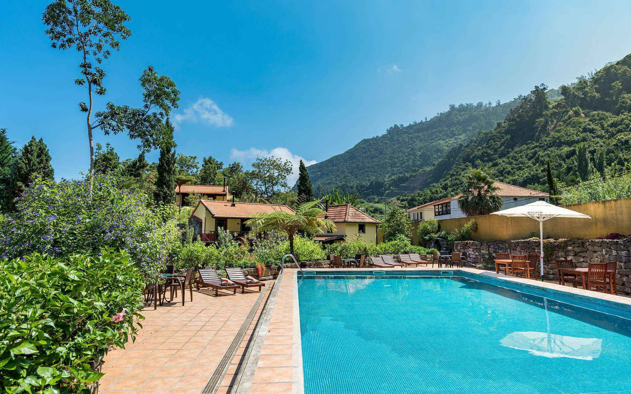 Piscine du Pestana Quinta do Arco, hôtel de tourisme rural à Madère, avec transats, végétation, villas et montagnes