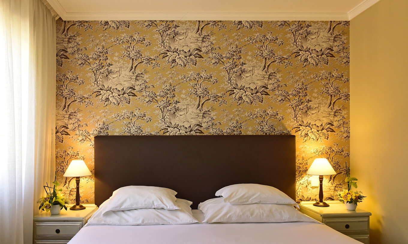 La Suite avec Jacuzzi du Pestana Village a un lit double avec tête de lit et couvre-lit marron, et papier peint