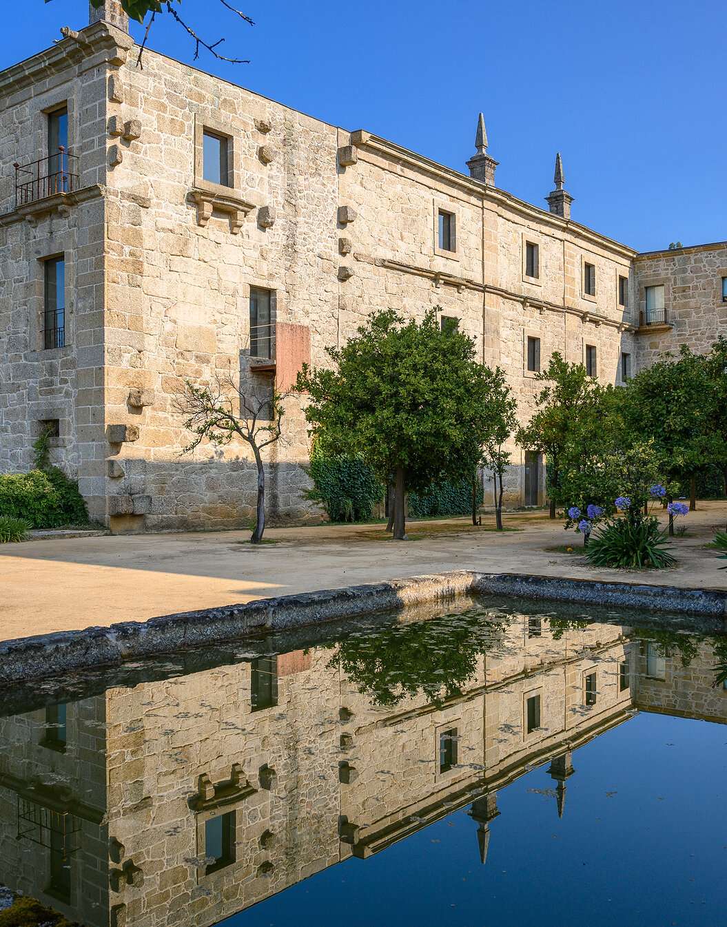 Vue extérieure de l'immeuble de la Pousada Mosteiro Amares, un hôtel historique à Gerês, en pierre avec un lac en face