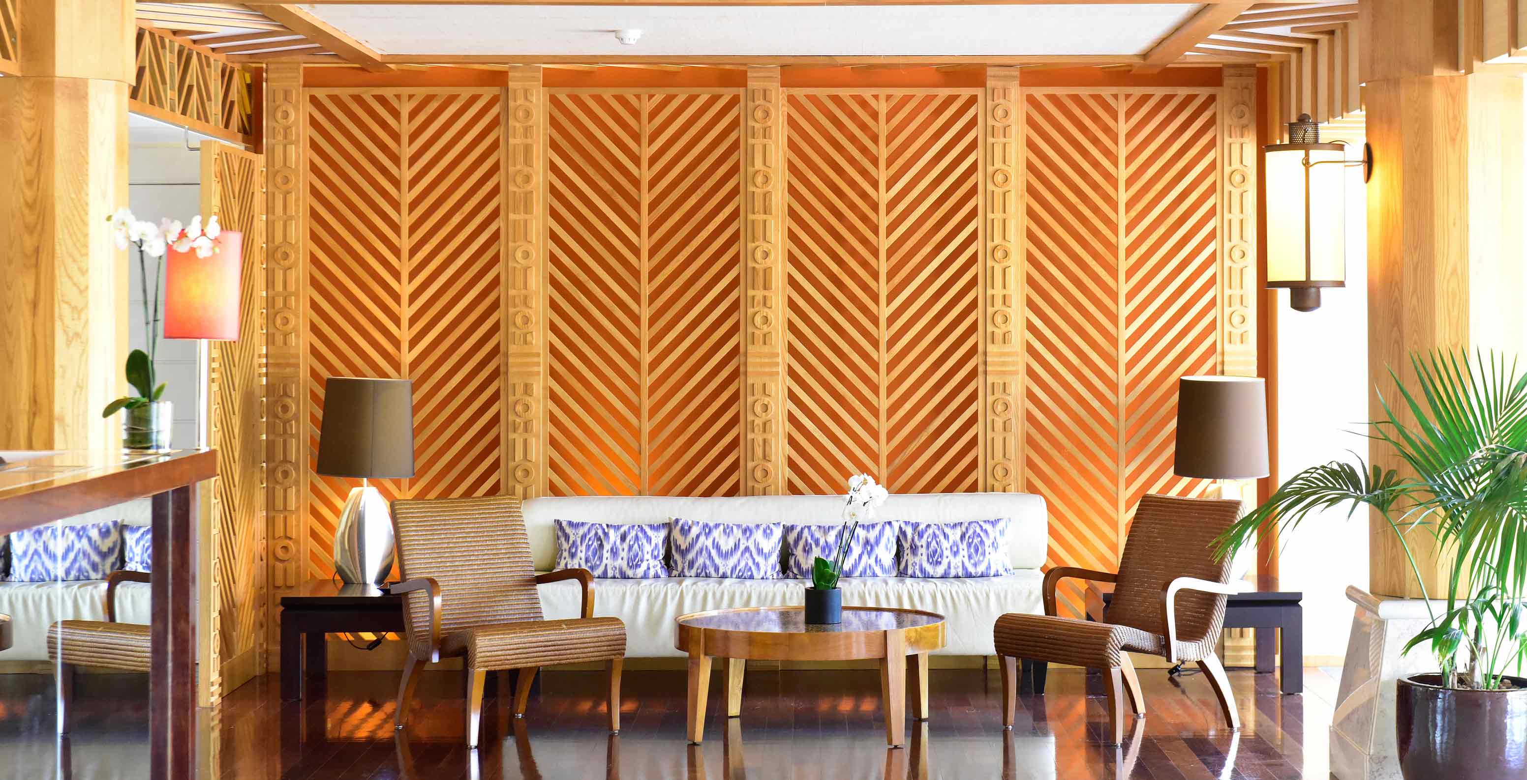 Canapé avec coussins, fauteuils et table basse dans salon décor bois Pestana Porto Santo